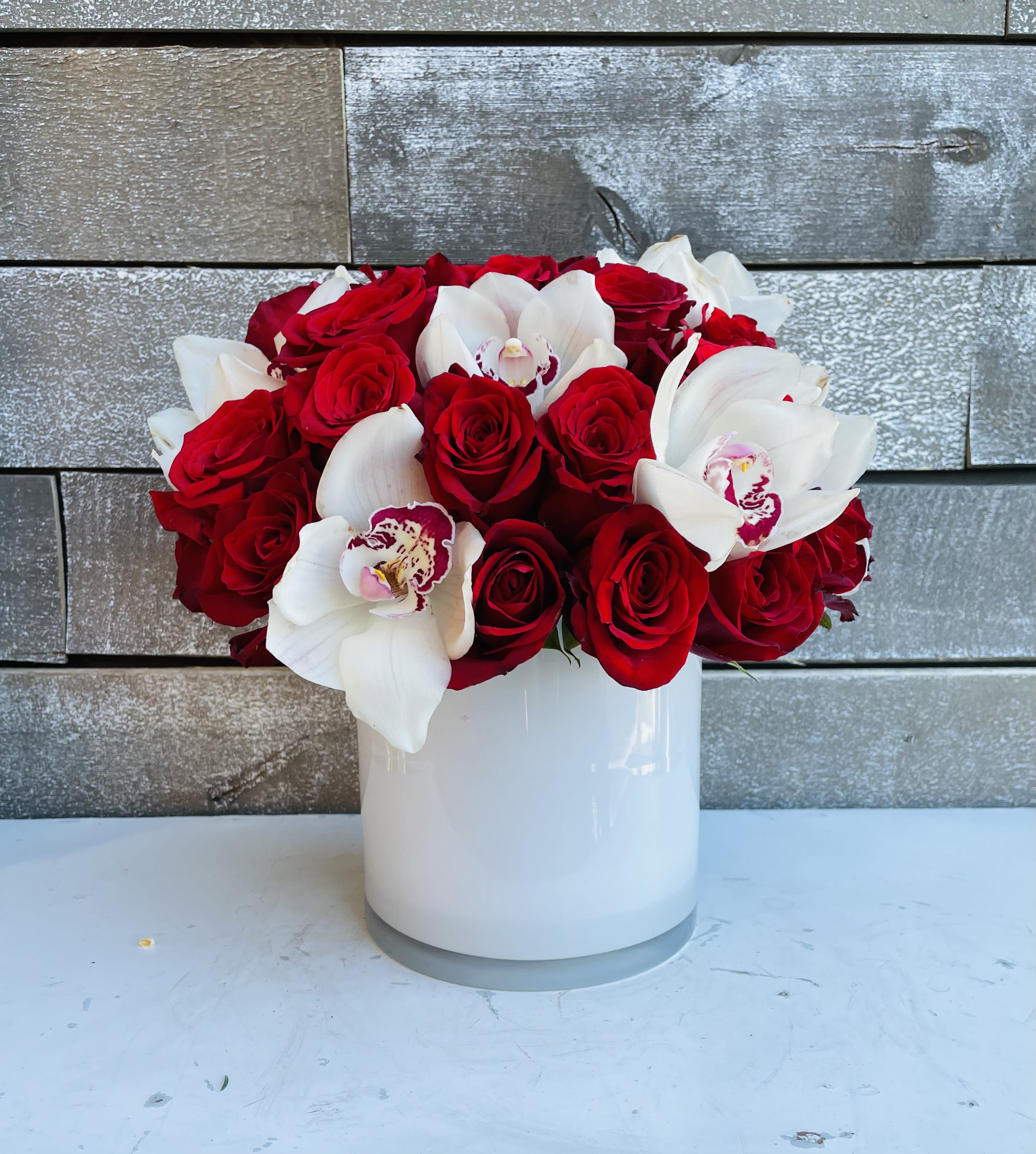 Red roses and white orchids arranged in a white vase
