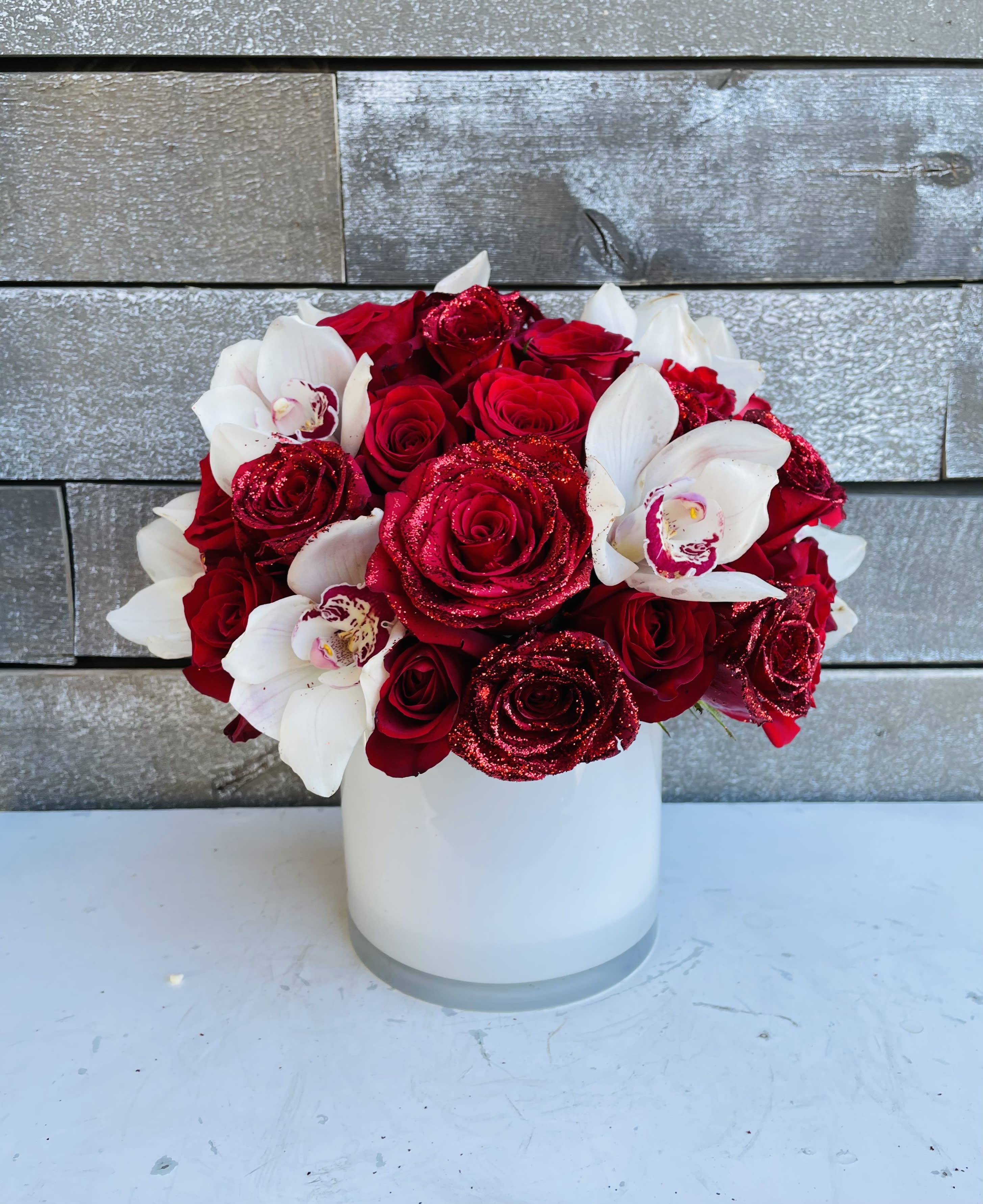 Red roses and white orchids arranged in a white vase