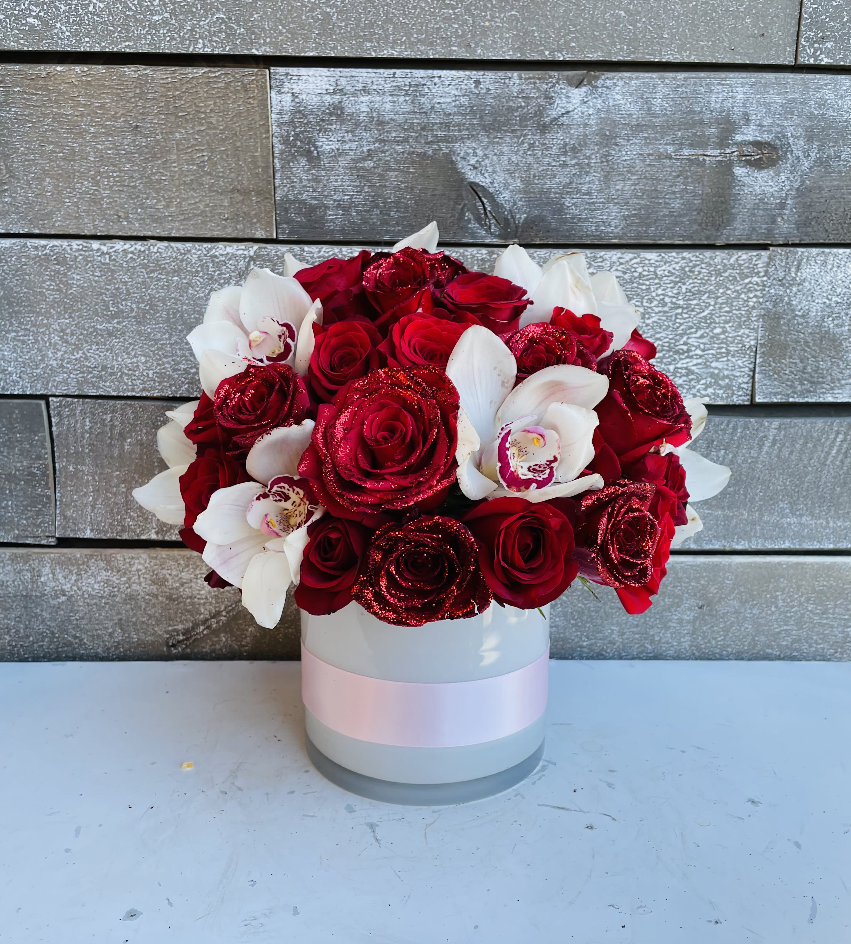 Red roses and white orchids in a round white box
