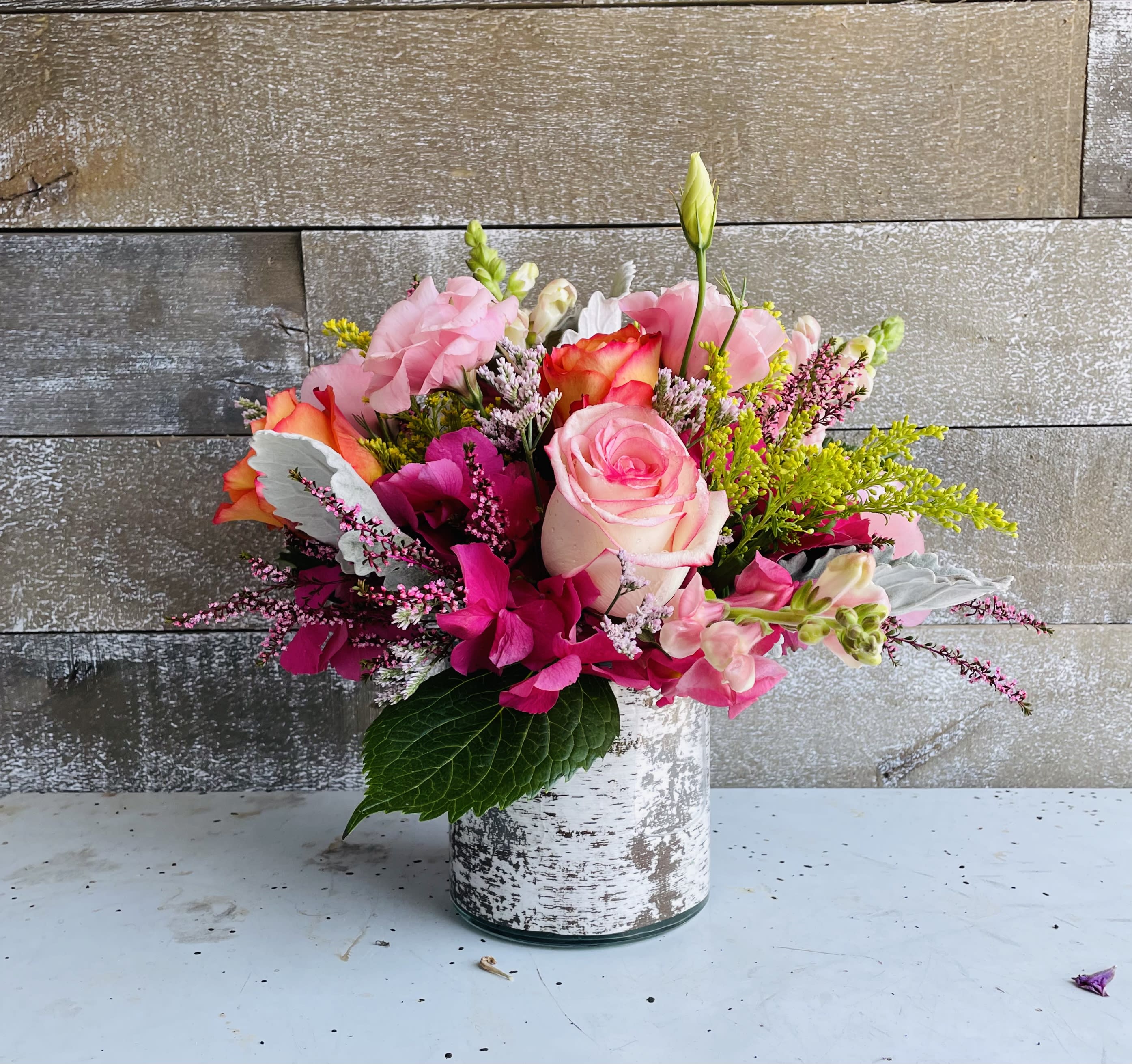 Pink and orange mixed flower arrangement in a white vase
