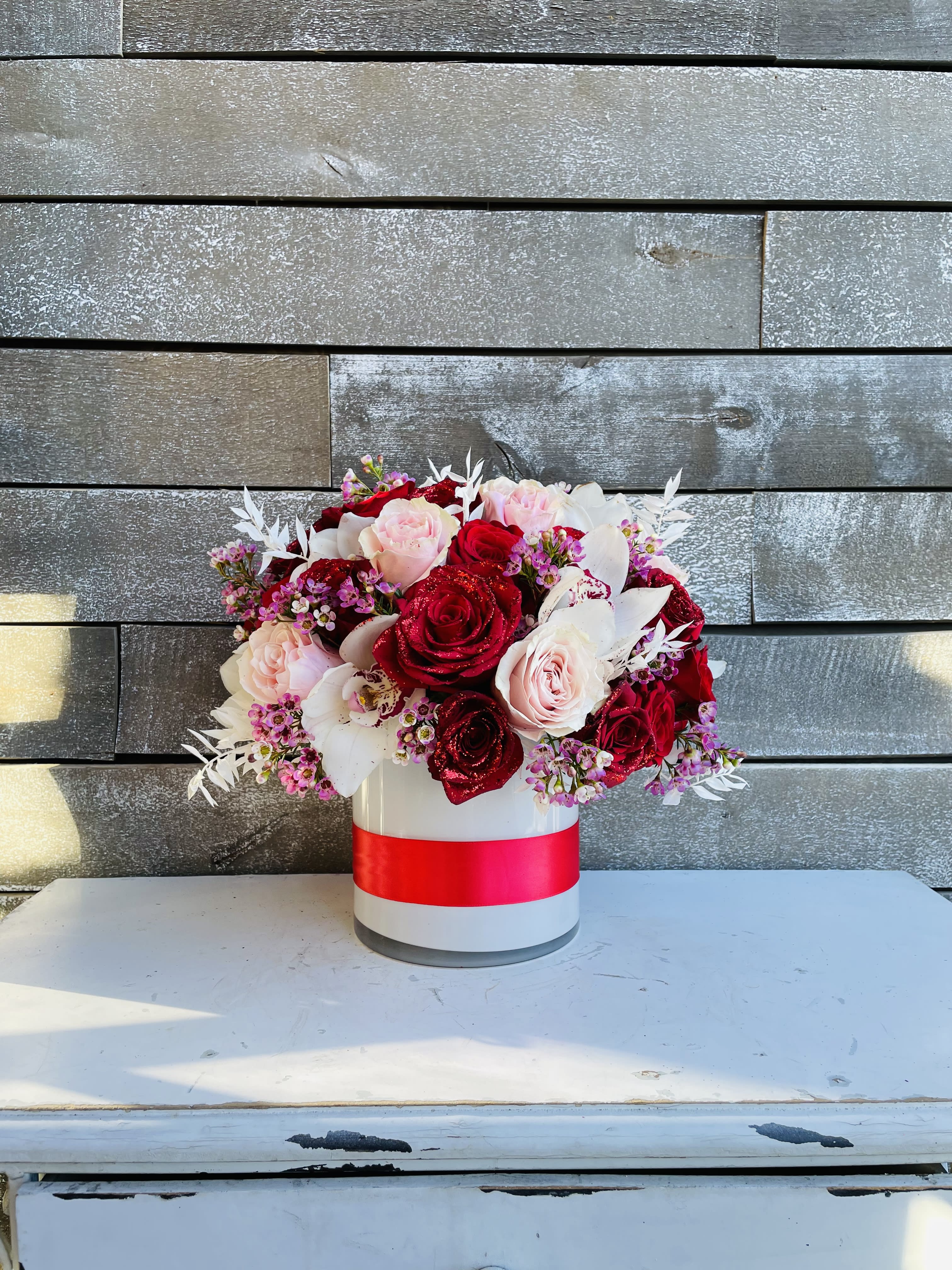 Bouquet of red and blush roses in a white hat box with a red ribbon