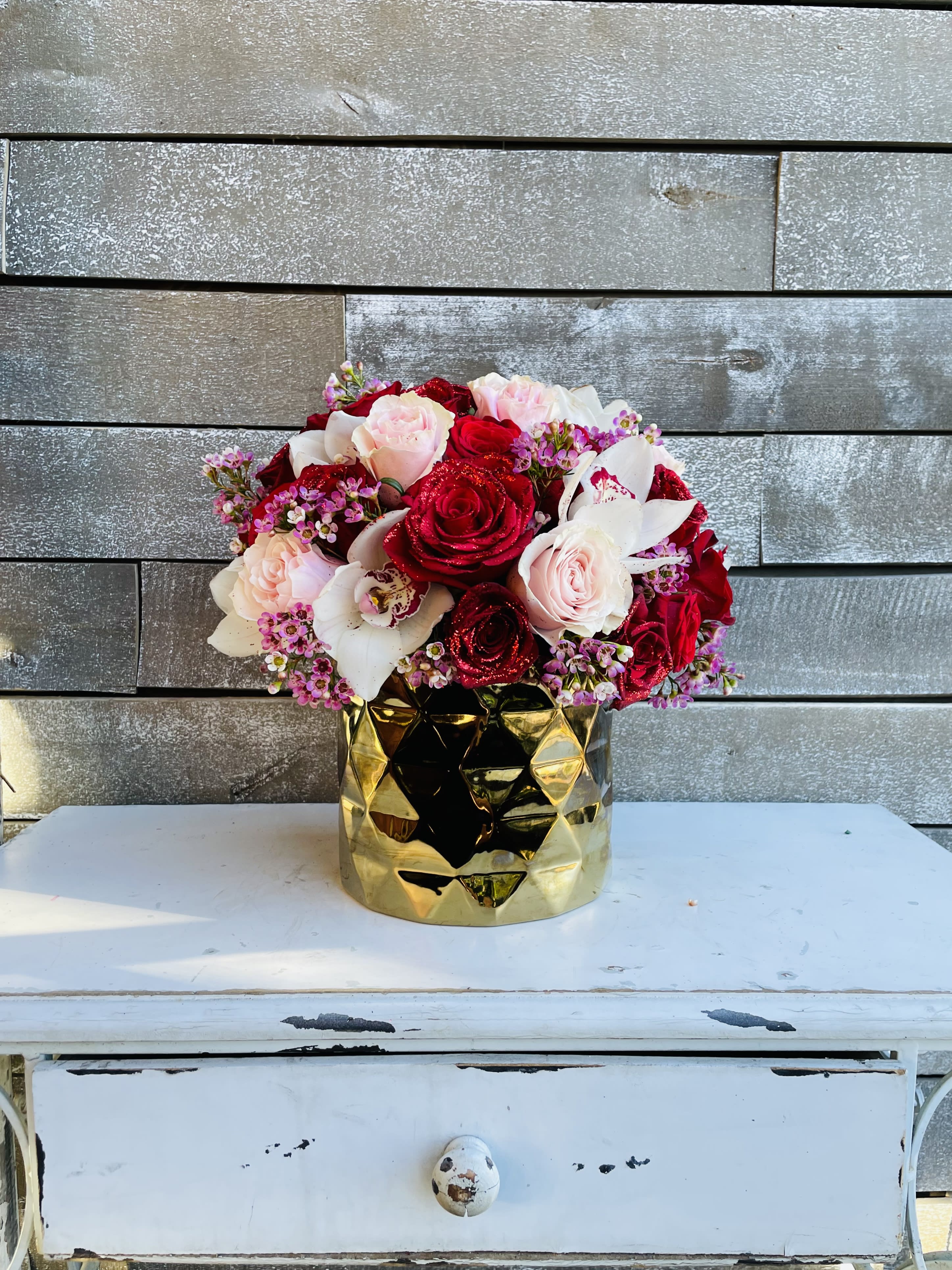 Bouquet of red and blush roses in a gold vase