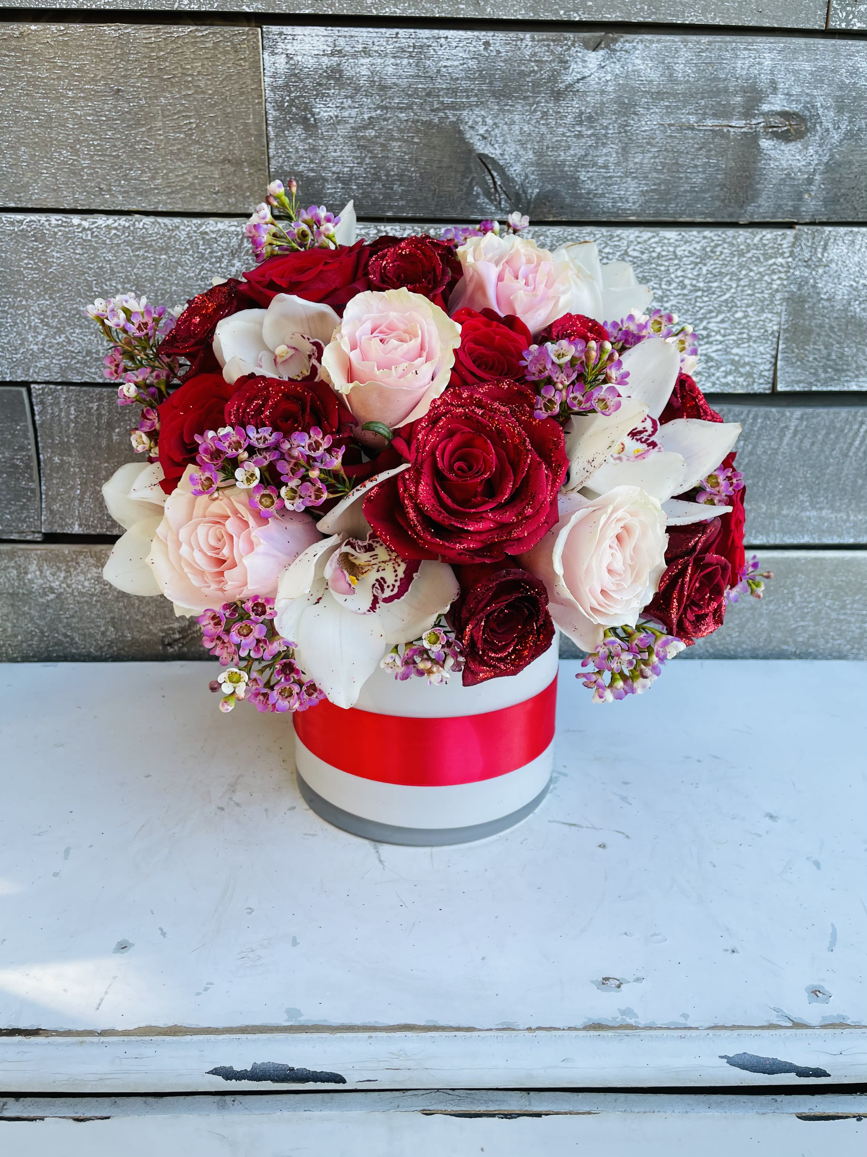 Bouquet of red and blush roses with white orchids in a round box