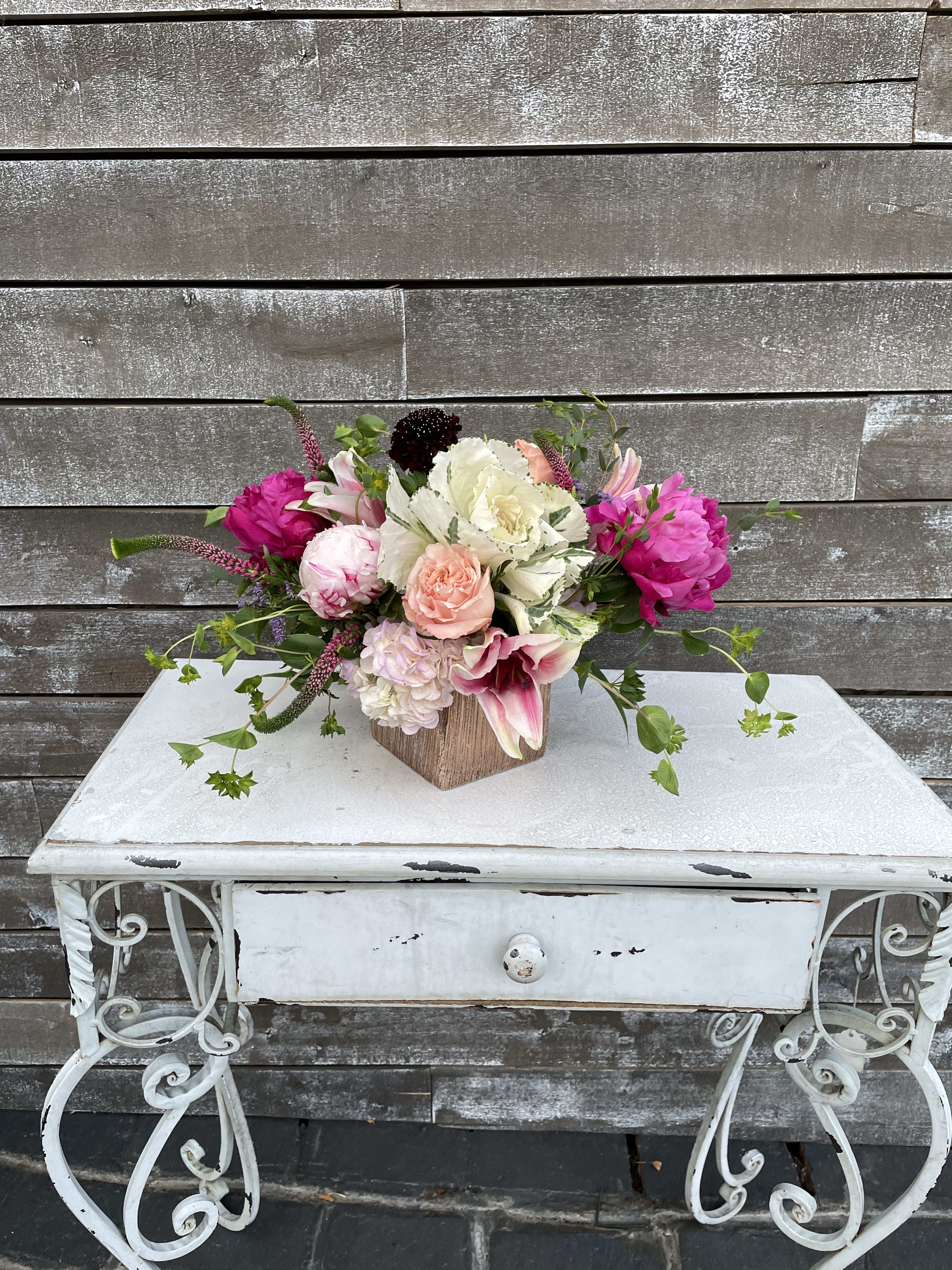 Mixed bouquet of pink, white, and peach flowers in a wooden cube vase