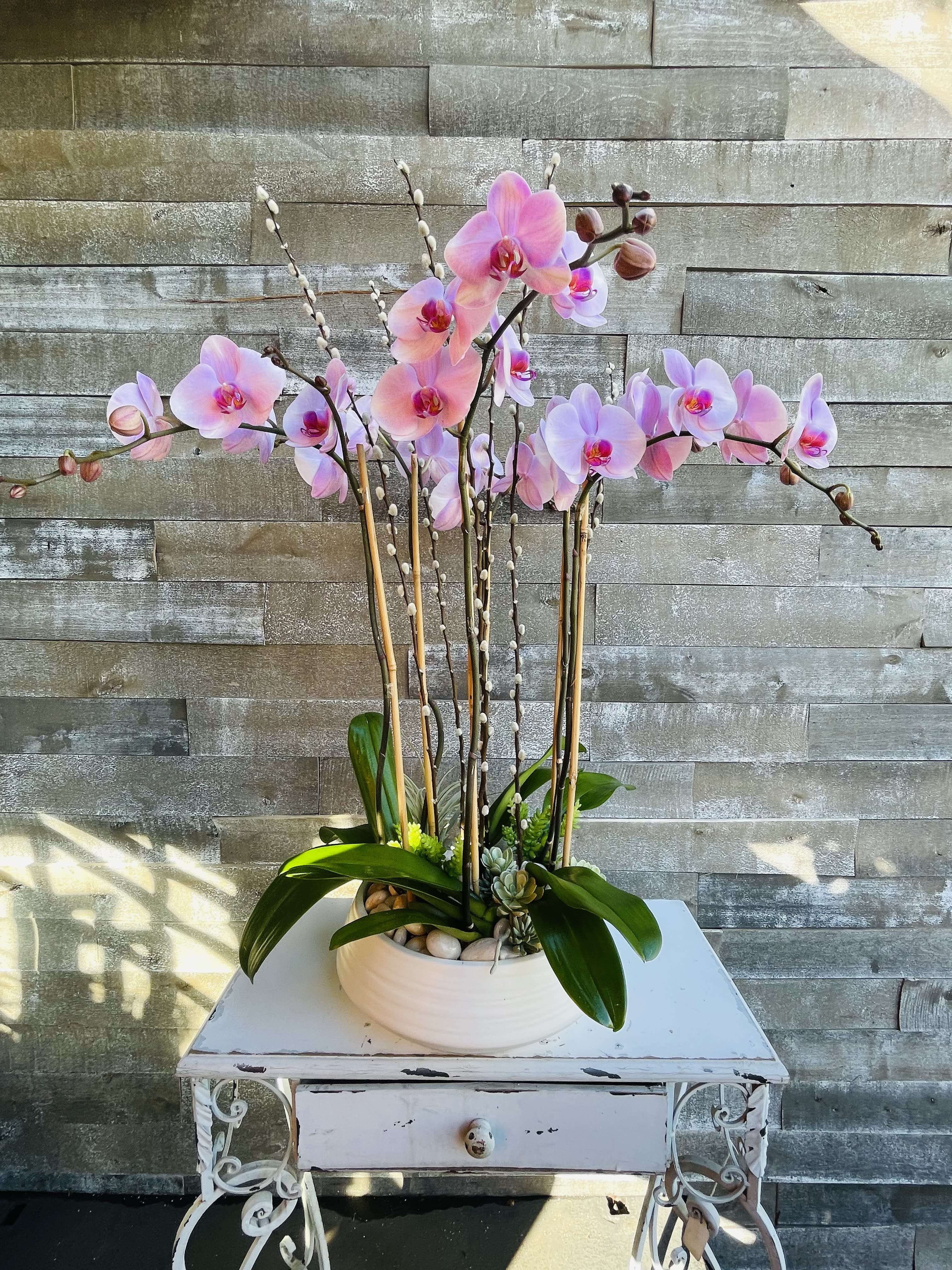 Pink orchid arrangement in a white bowl planter