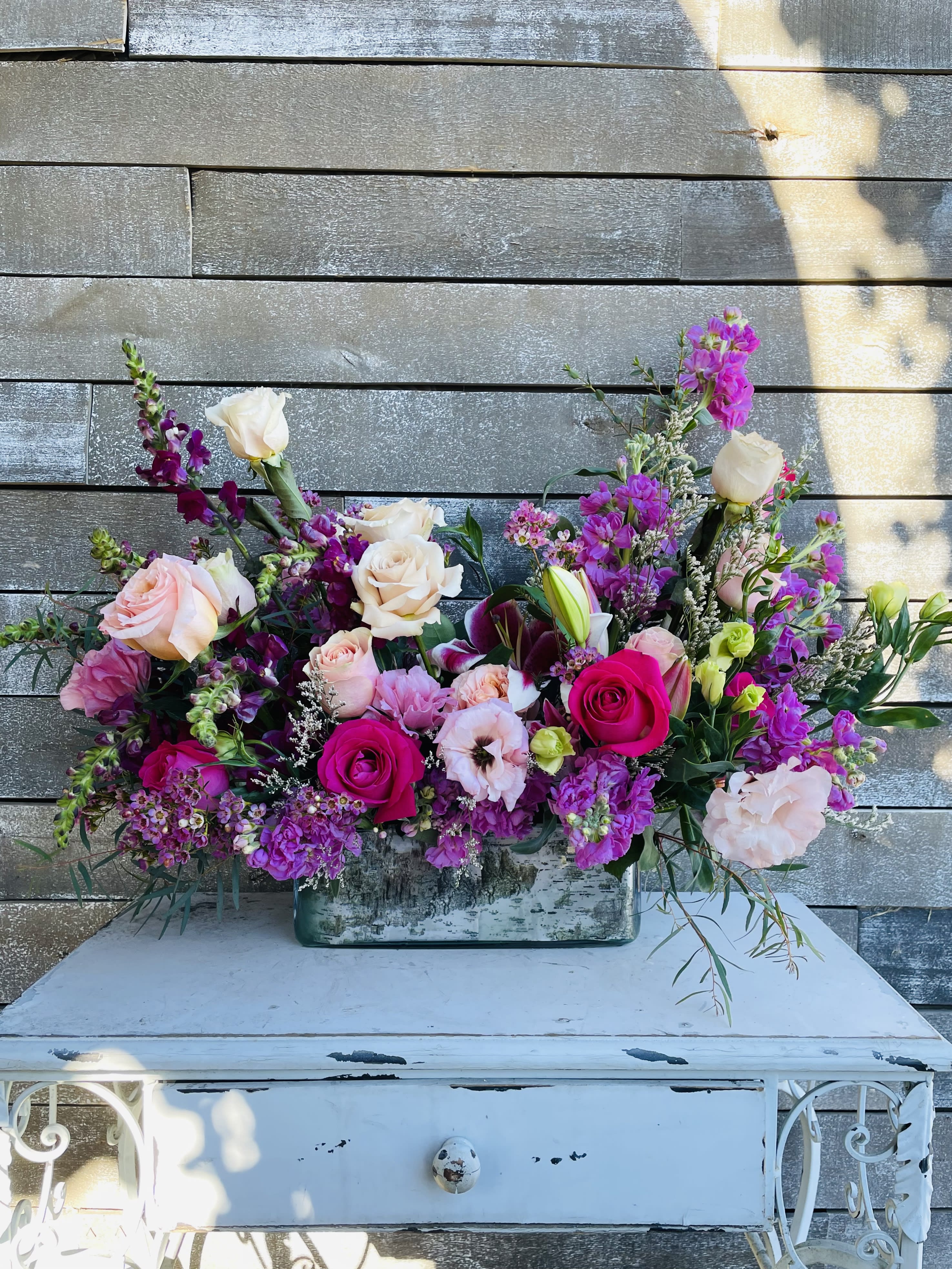 Large mixed bouquet of pink, purple, and white flowers in a rectangular vase