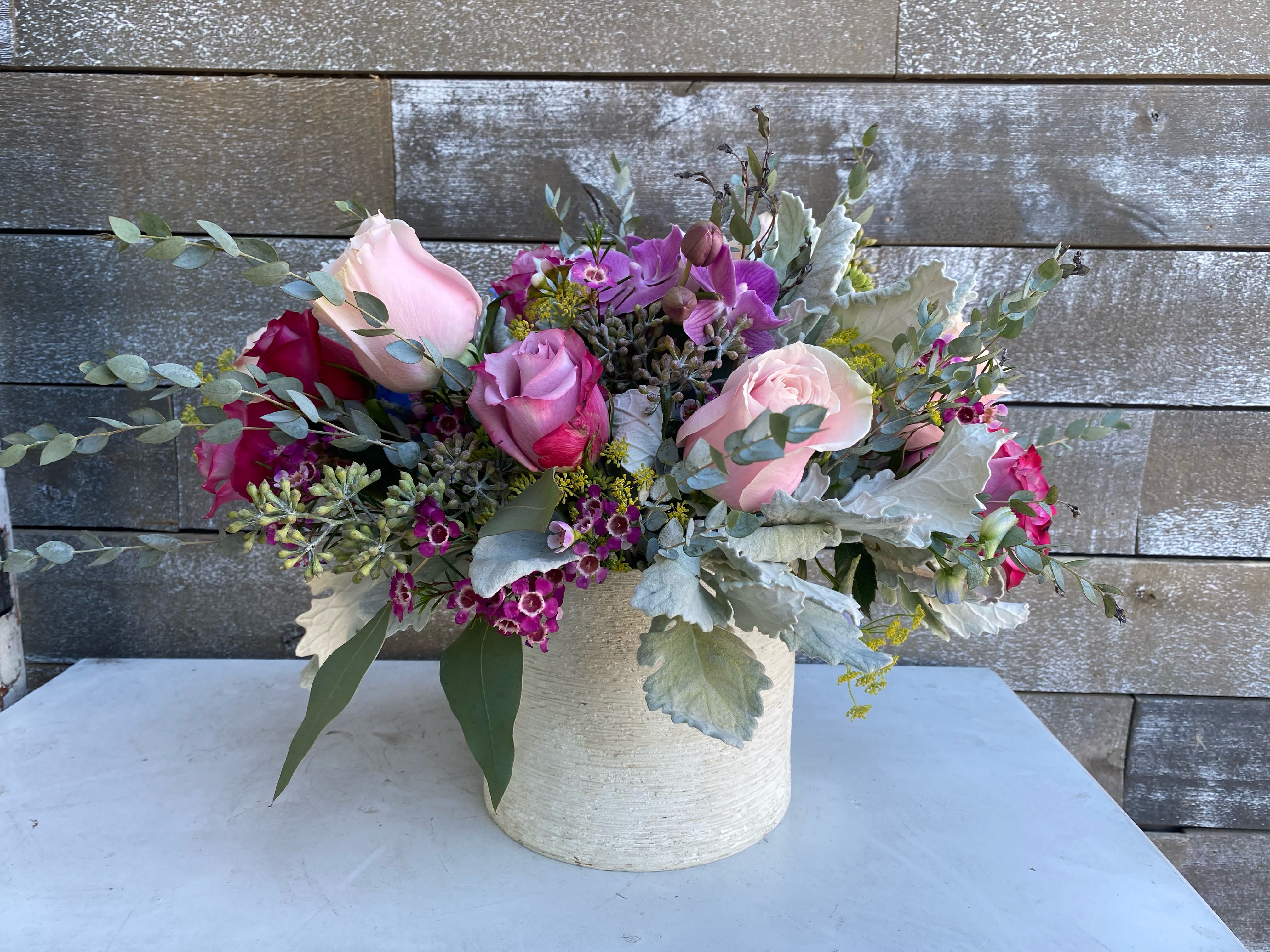 Pink and purple roses arranged in a white vase