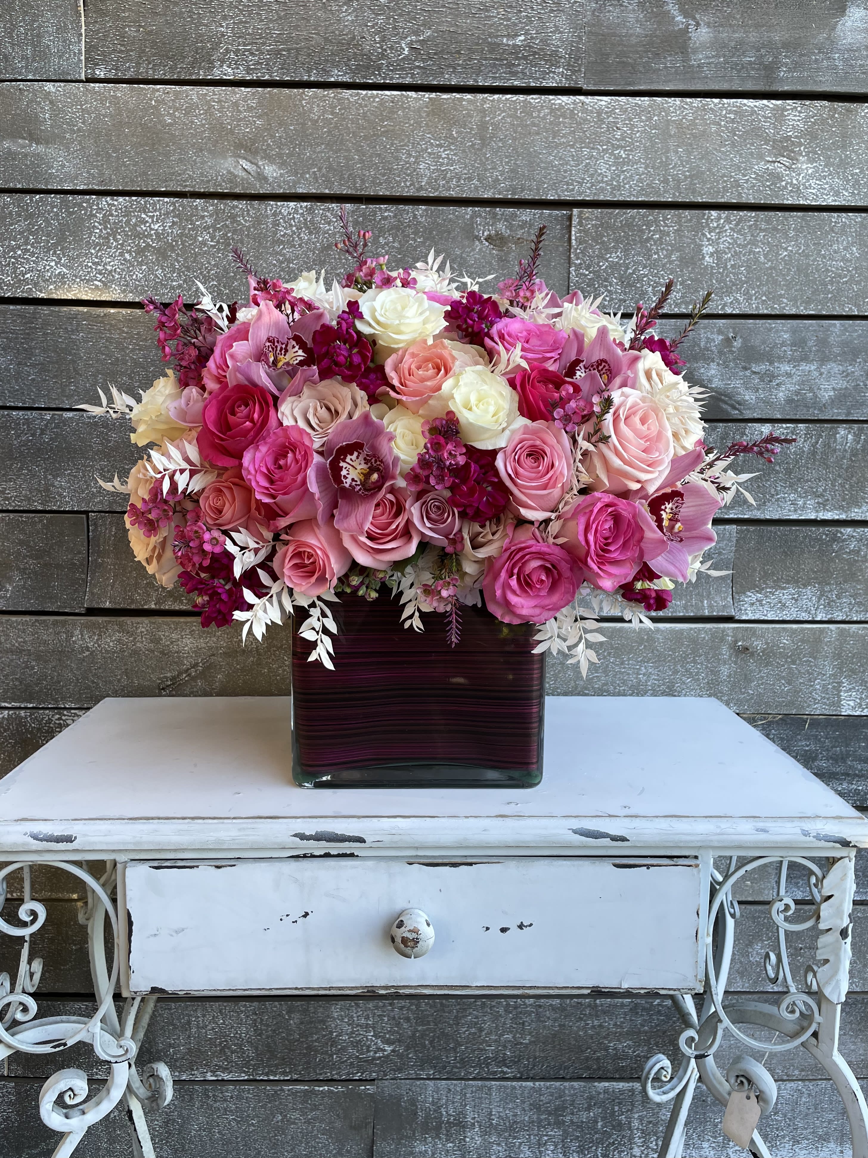 Pink and white rose bouquet in a square glass vase
