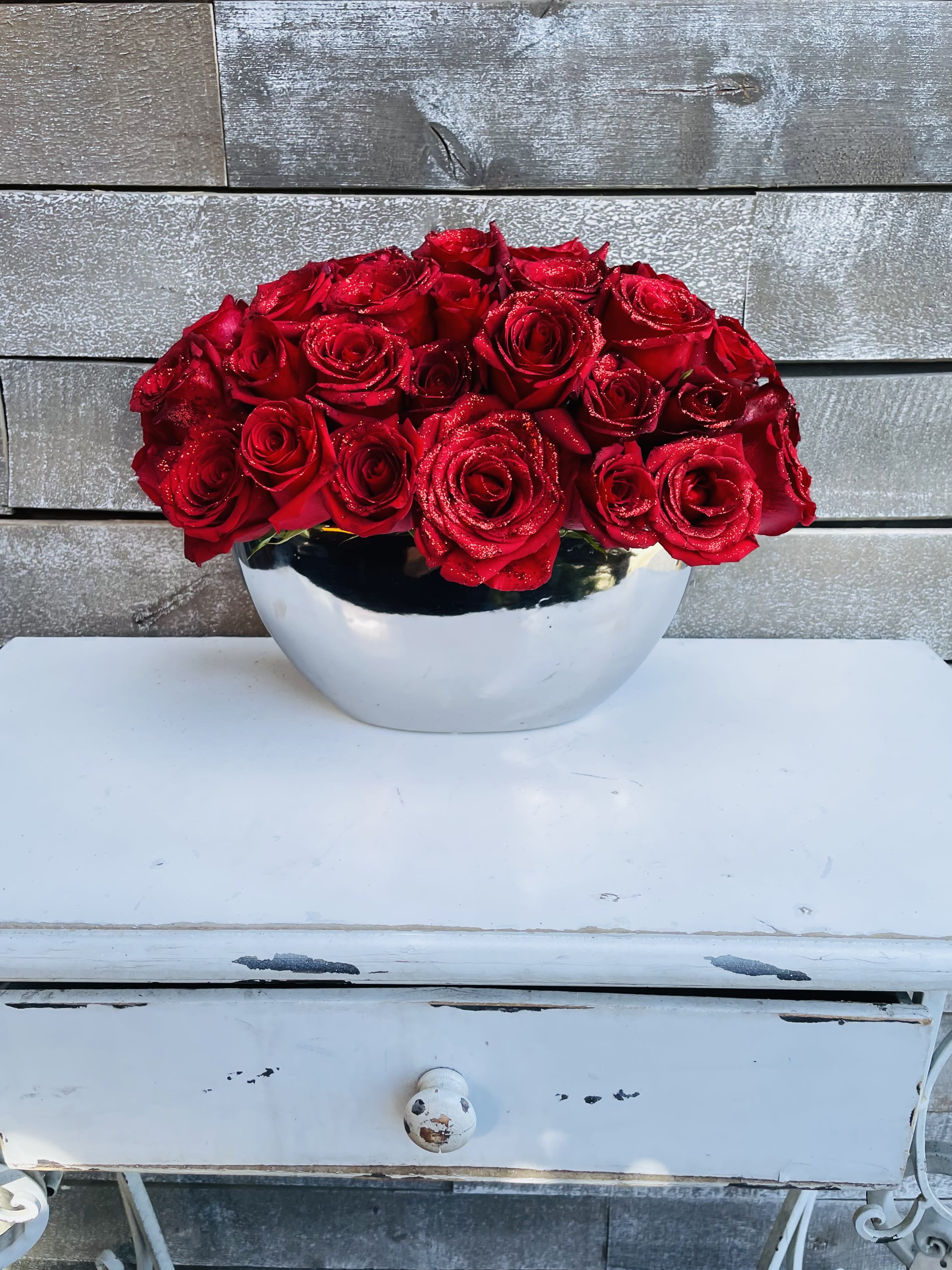 Red roses arranged in a silver bowl vase