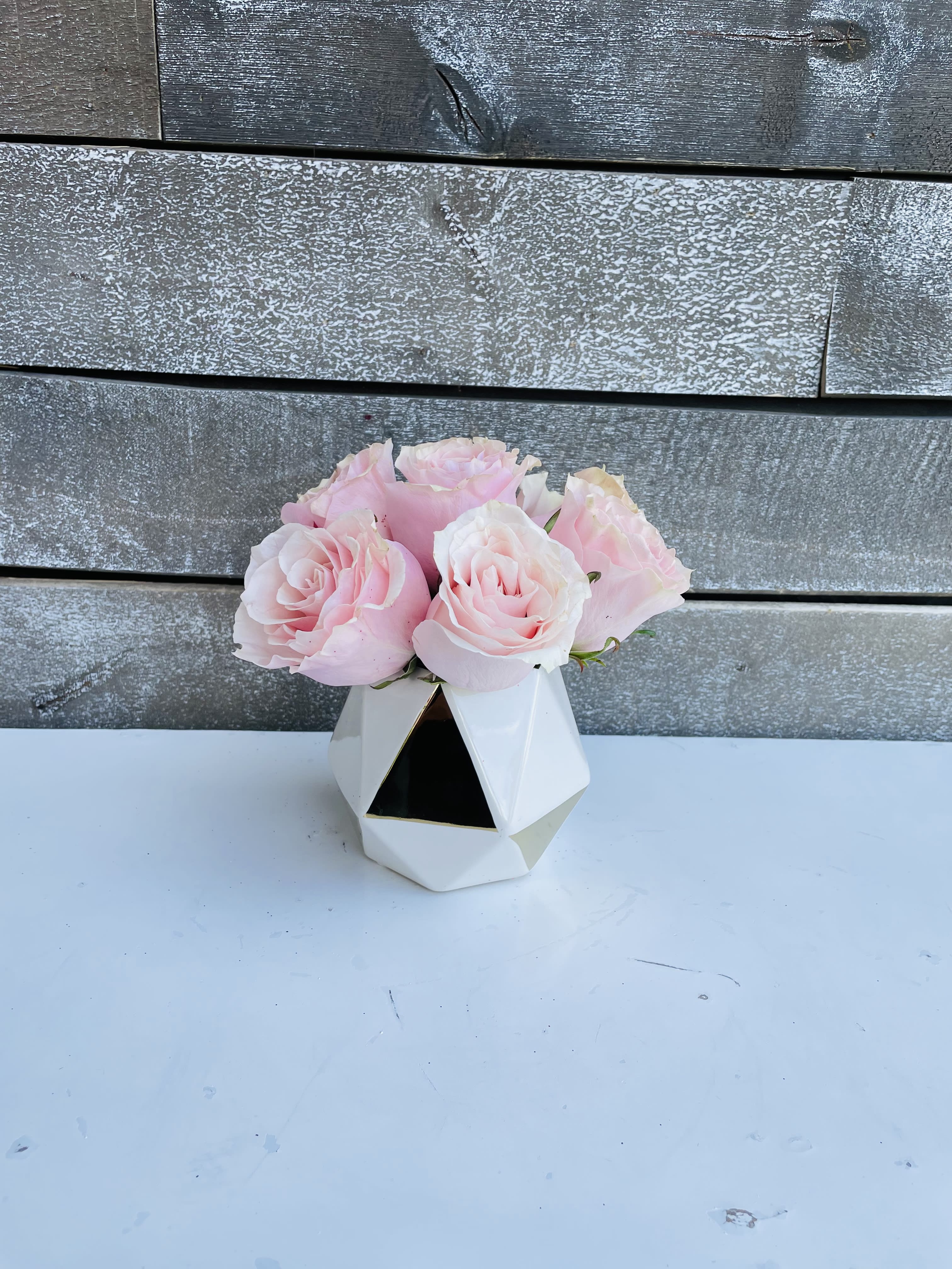Pink roses in a small geometric white vase