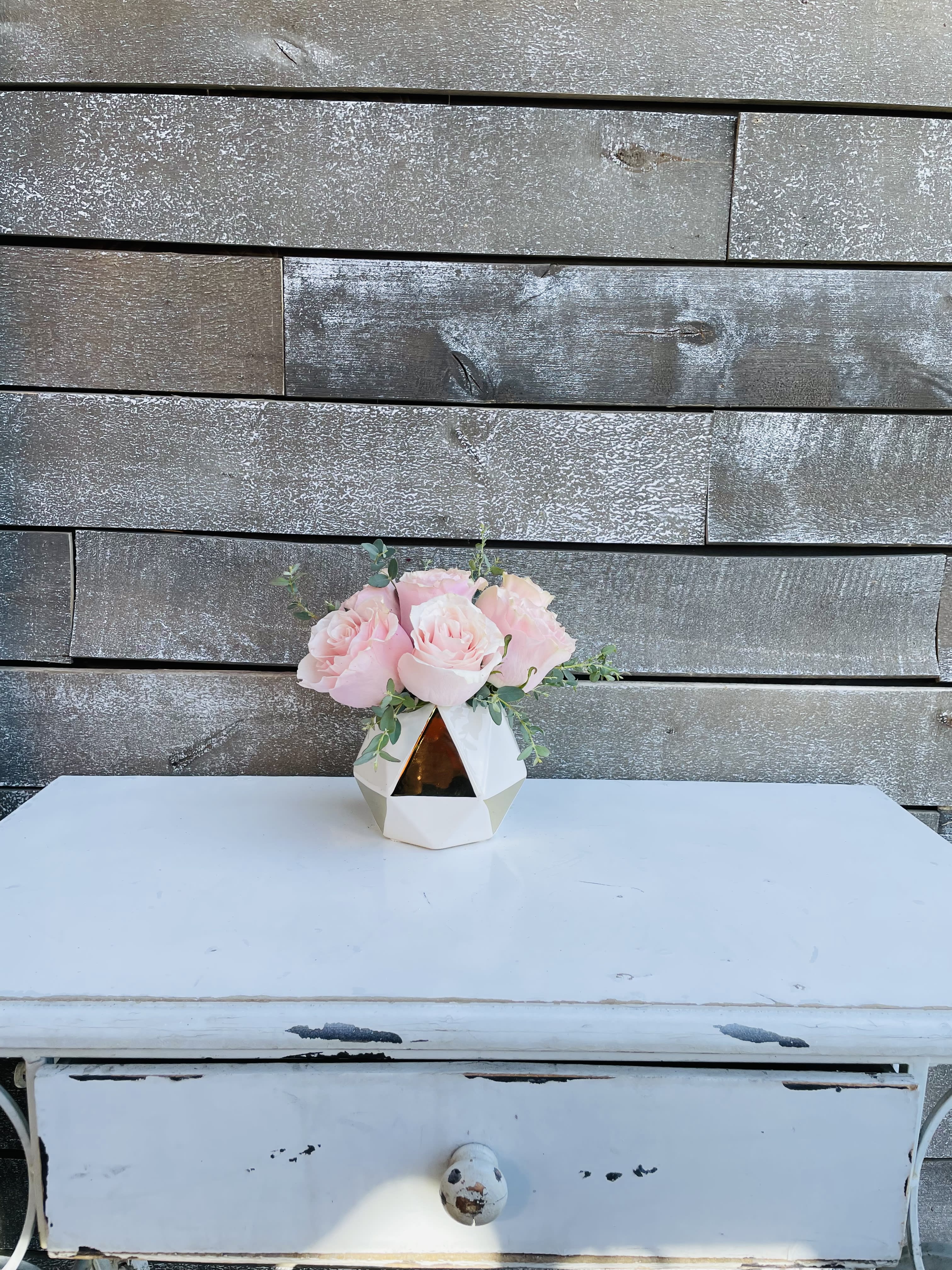 Pink roses in a geometric white vase on a table
