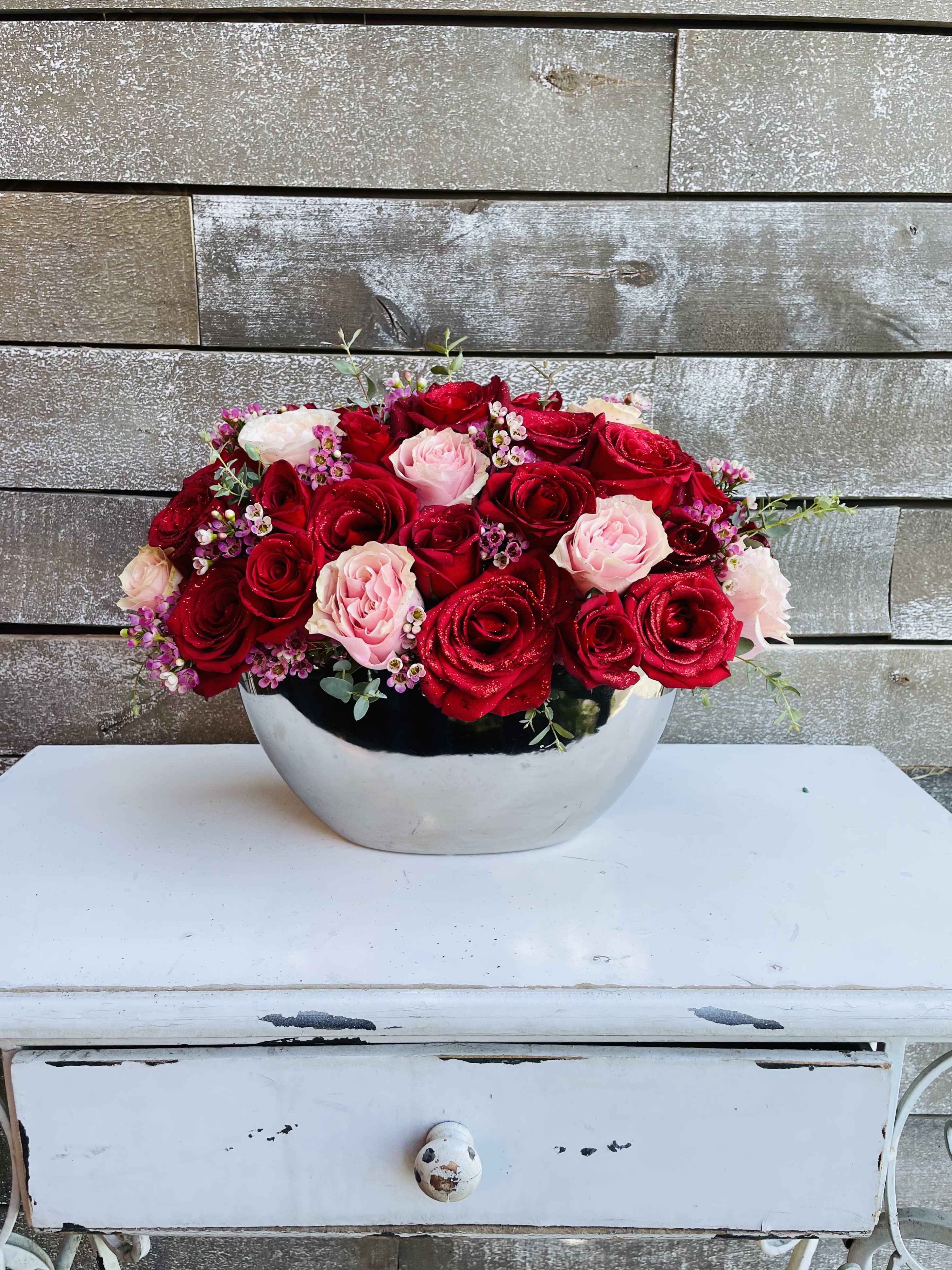 Red and pink roses arranged in a silver bowl