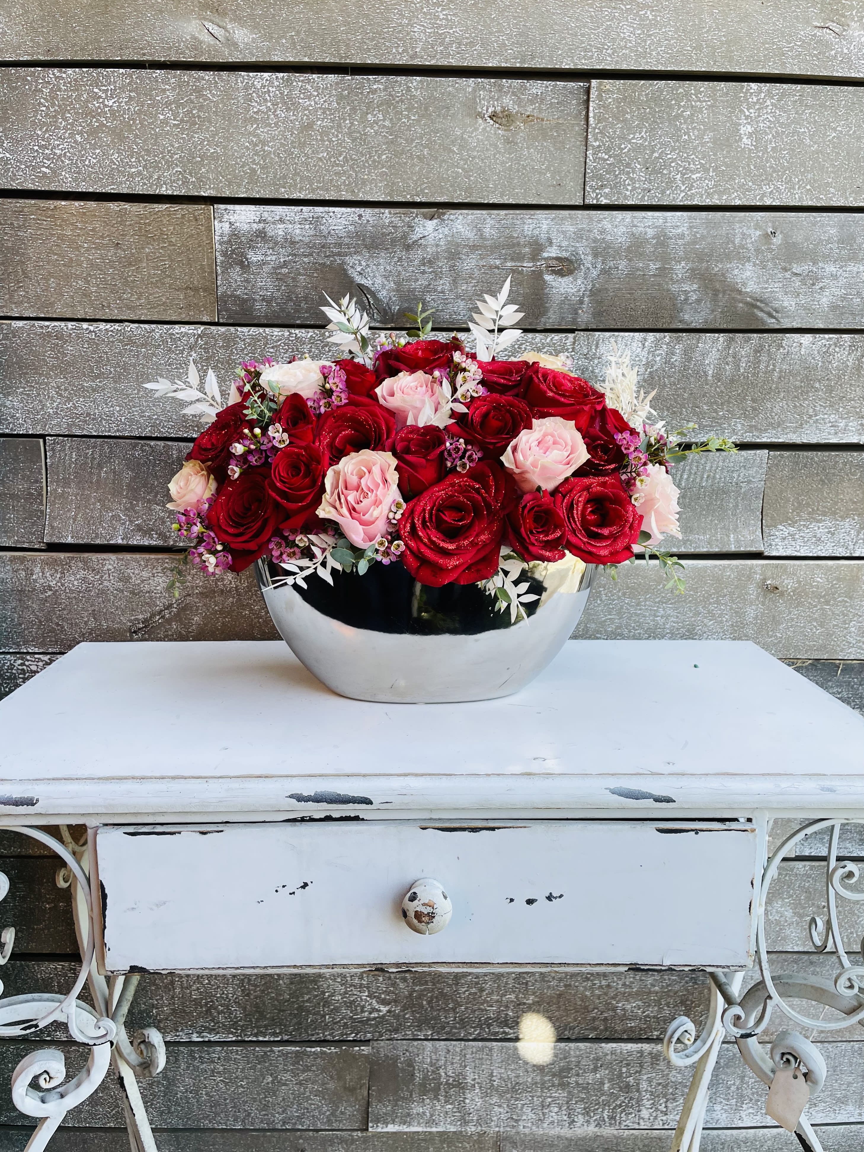 Red and pink roses arranged in a silver bowl vase