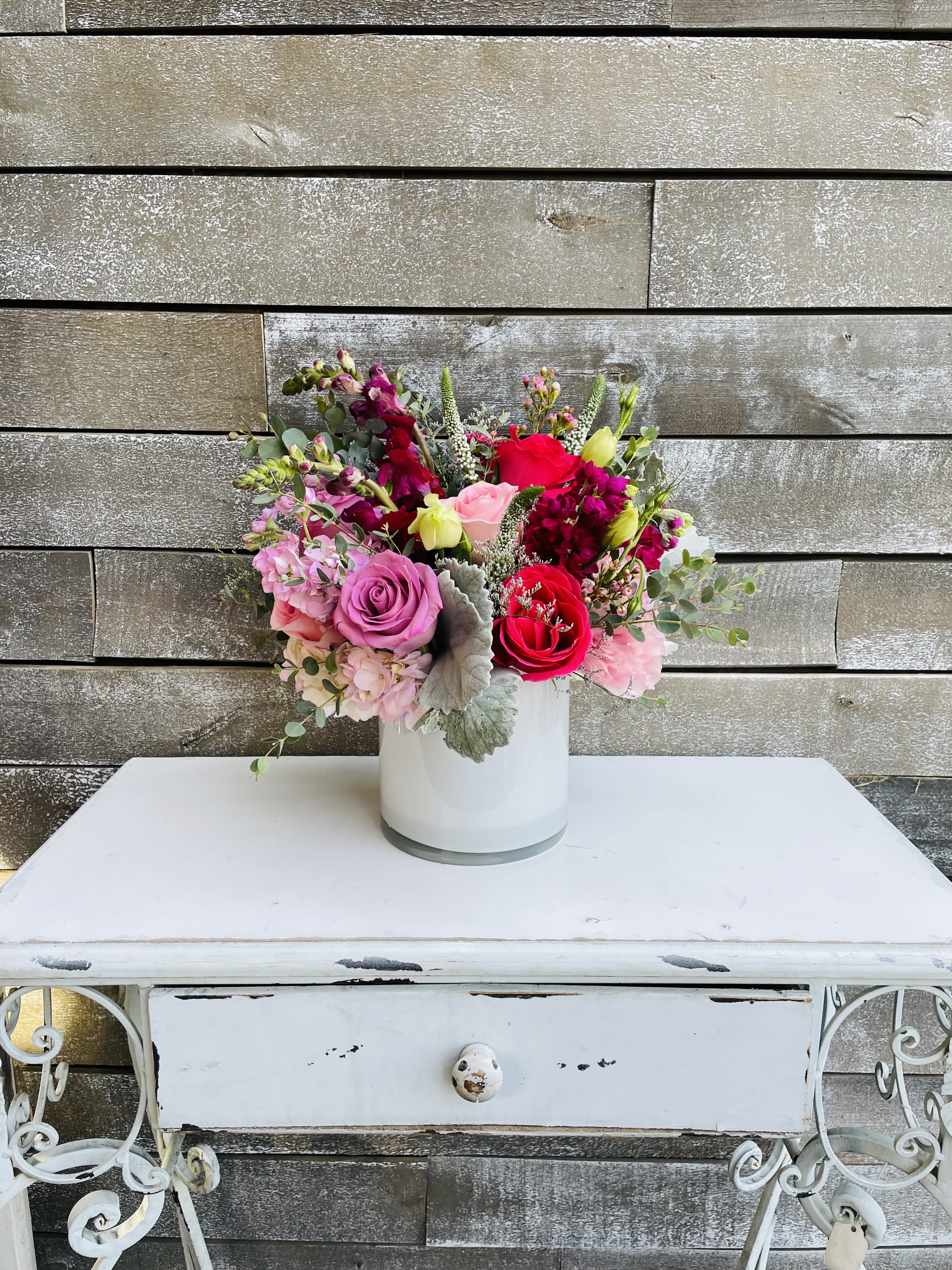 Mixed pink and red flower bouquet in a white vase
