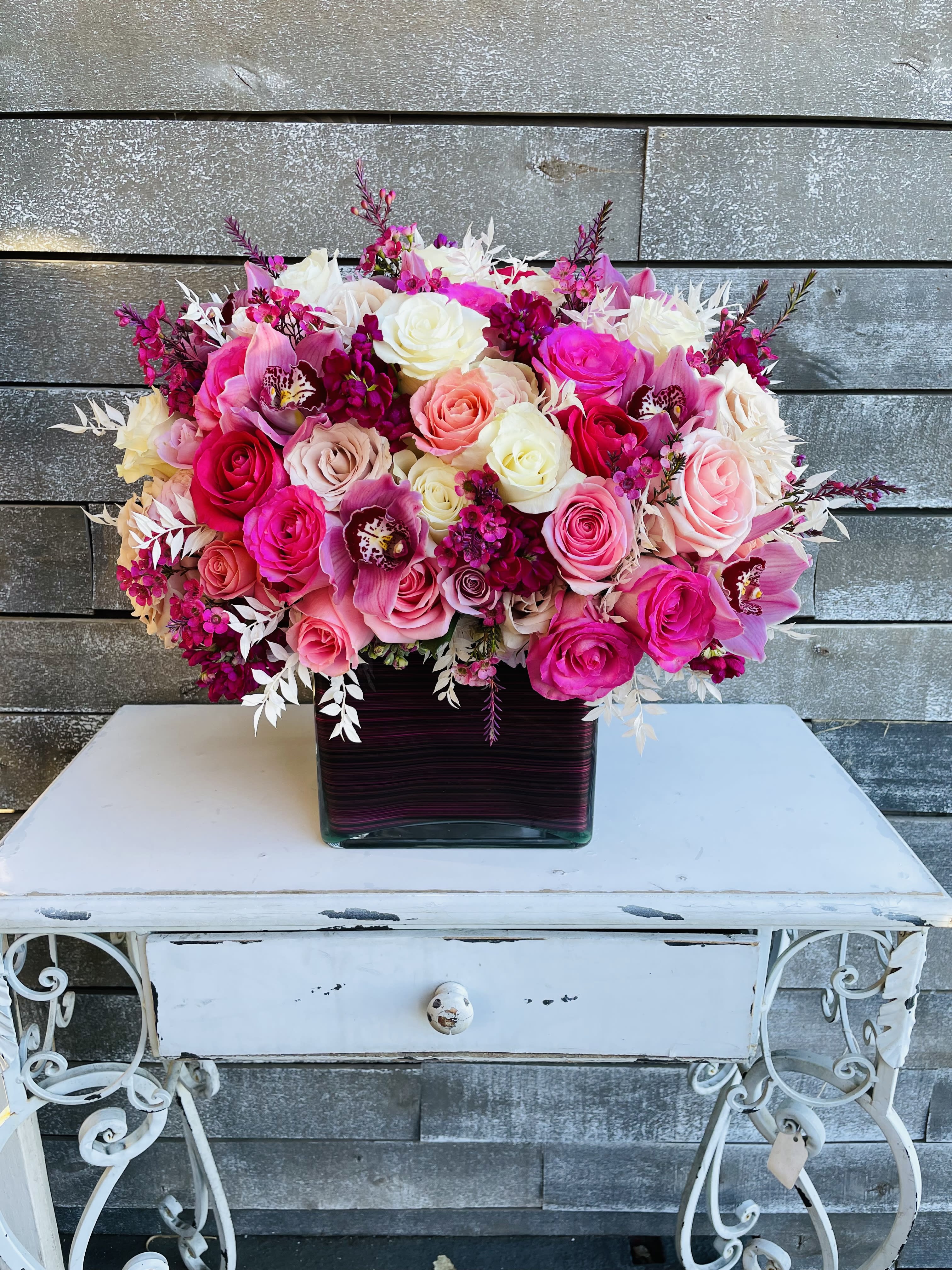 Pink and white rose arrangement in a square glass vase