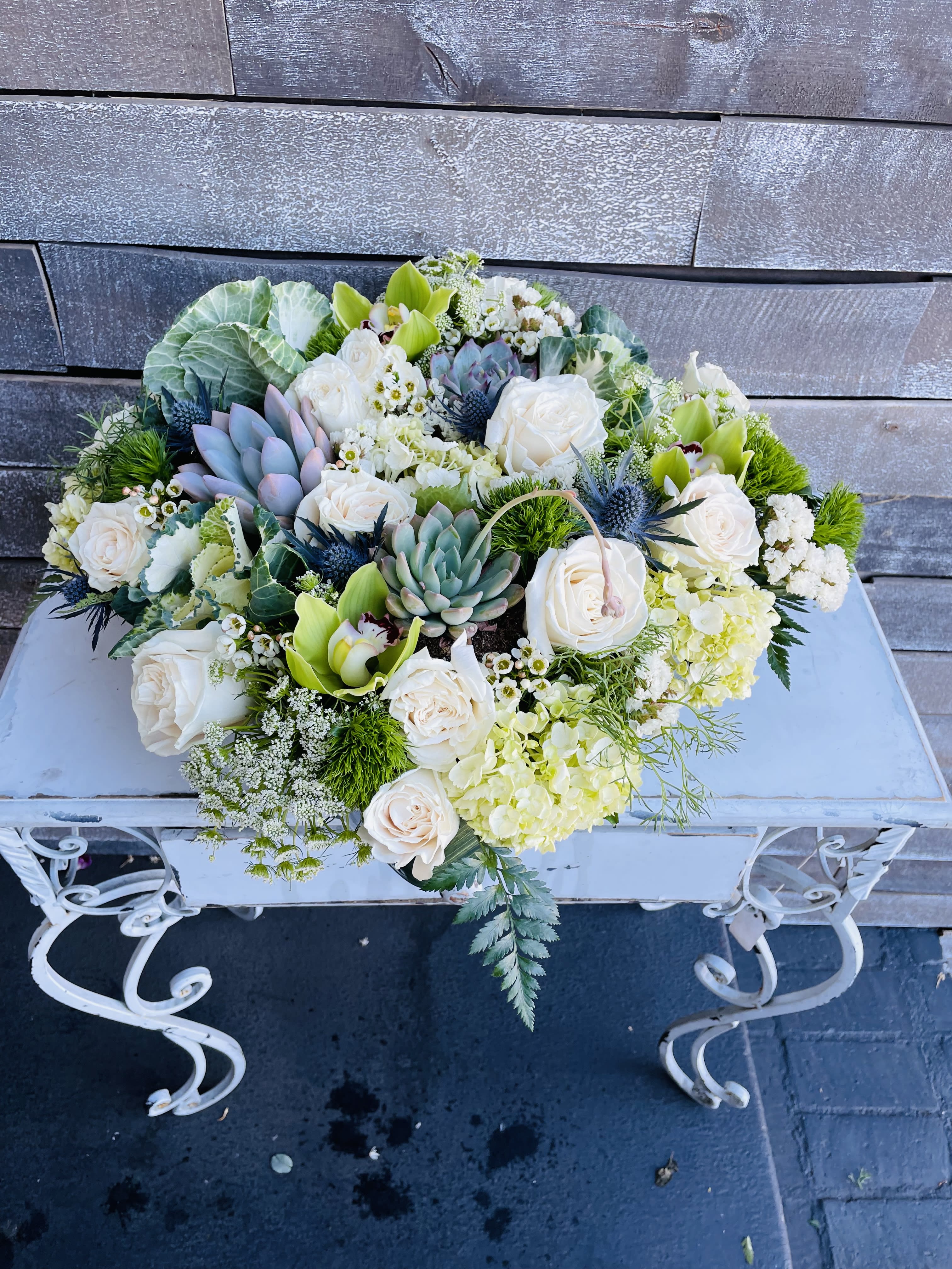 Low floral arrangement with white roses, succulents, and green orchids