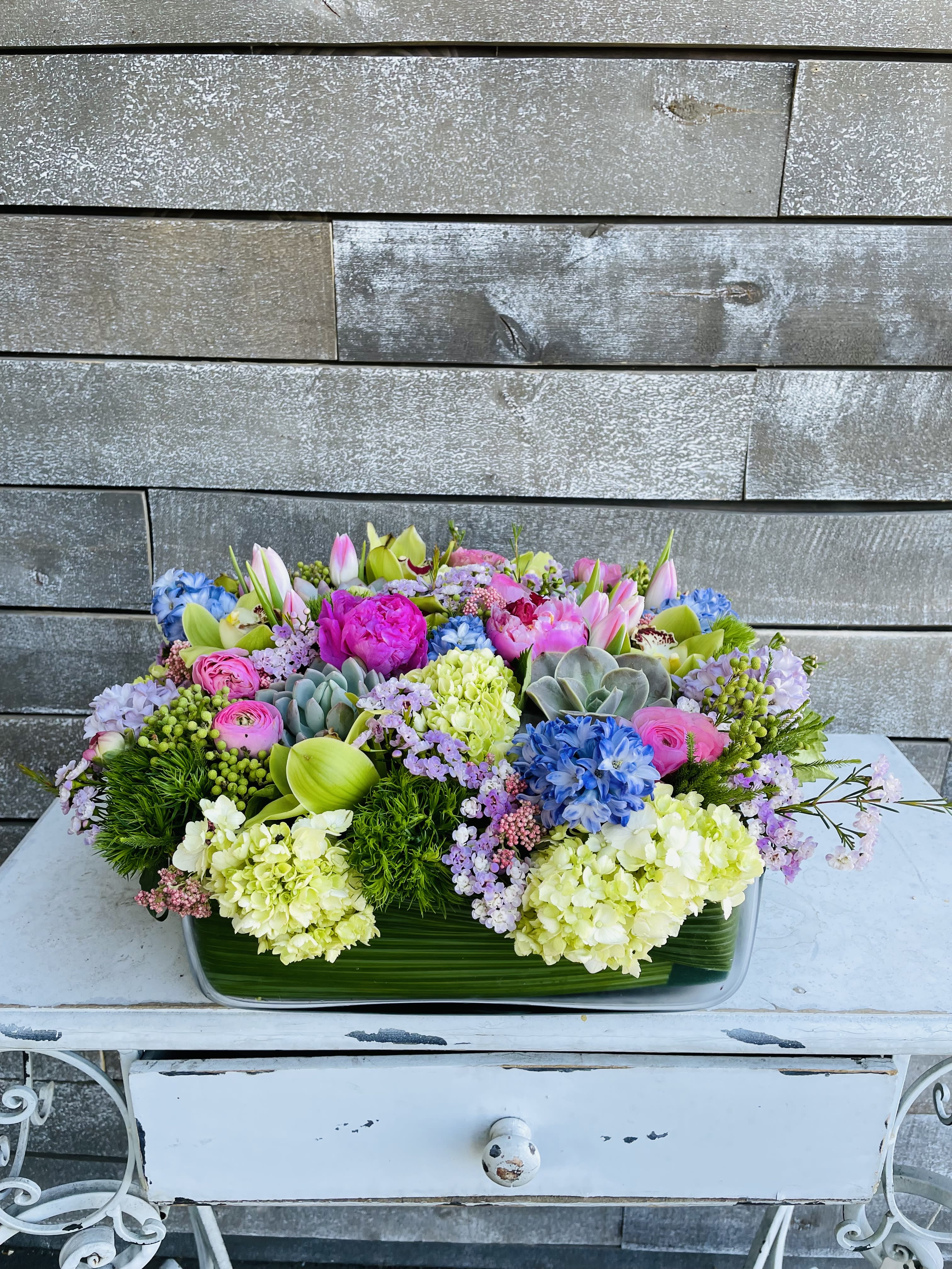 Colorful mixed flower arrangement in a rectangular glass vase
