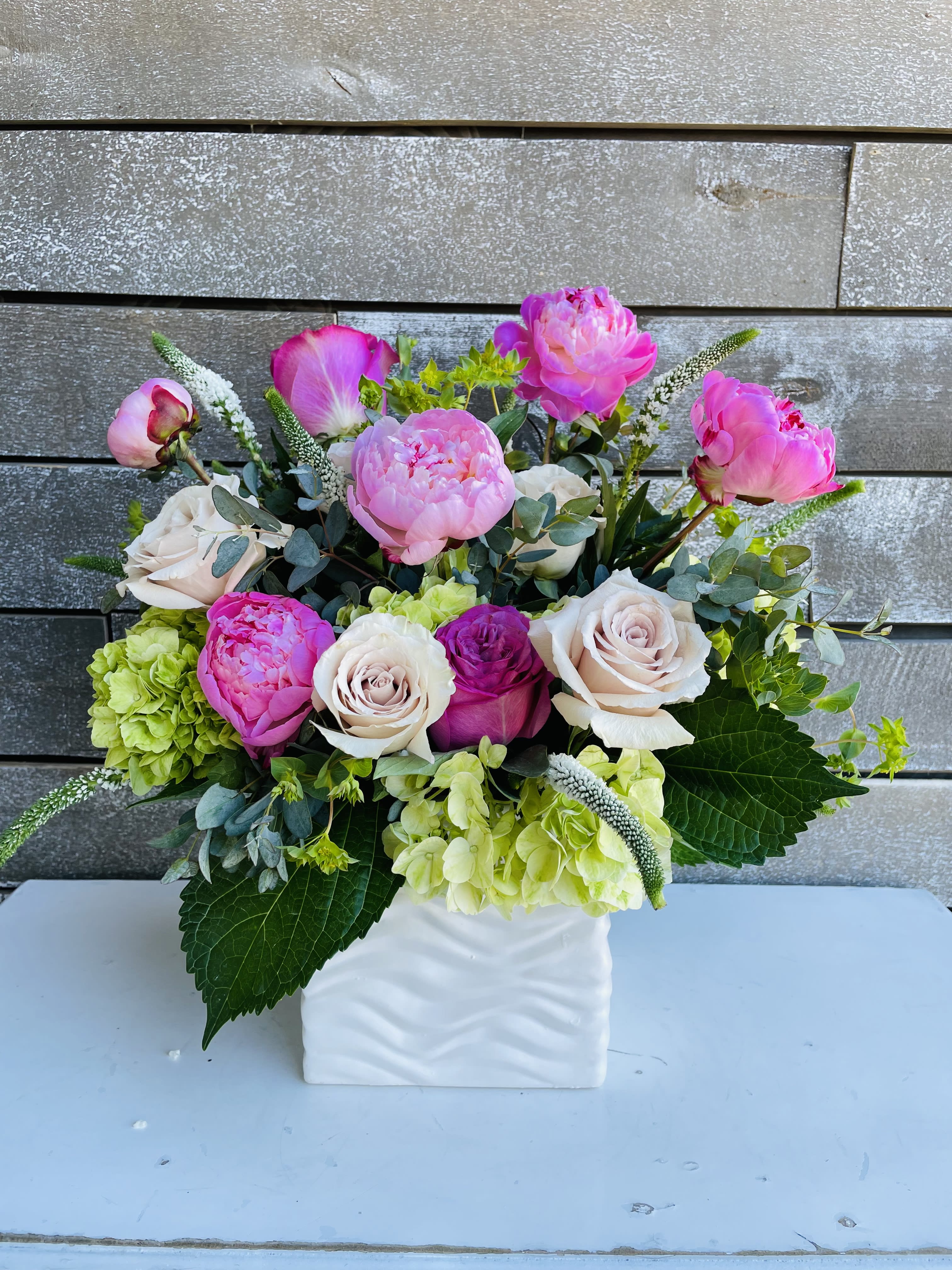 Pink and white flowers arranged in a white square vase