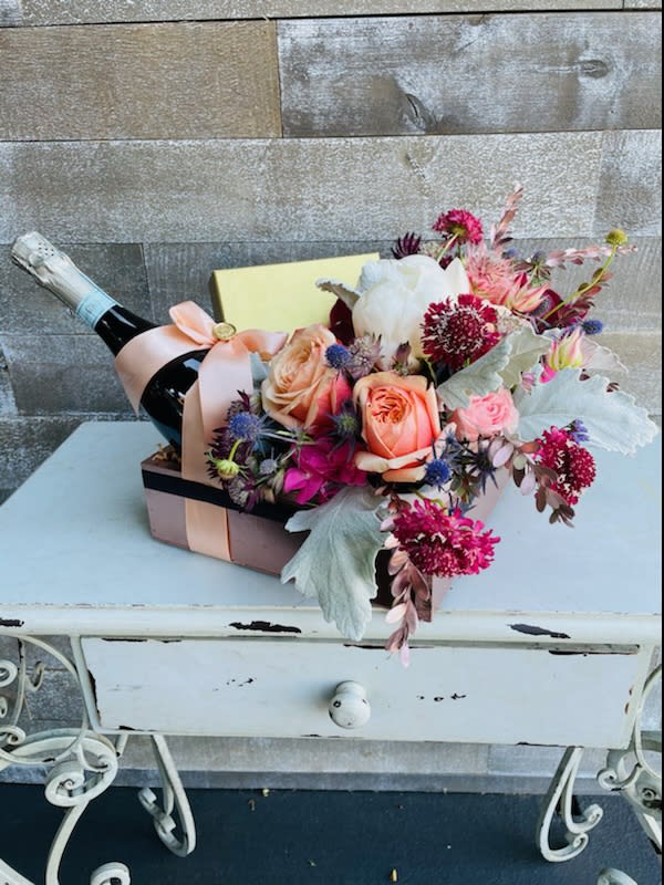 Flower arrangement in a gift box with a champagne bottle