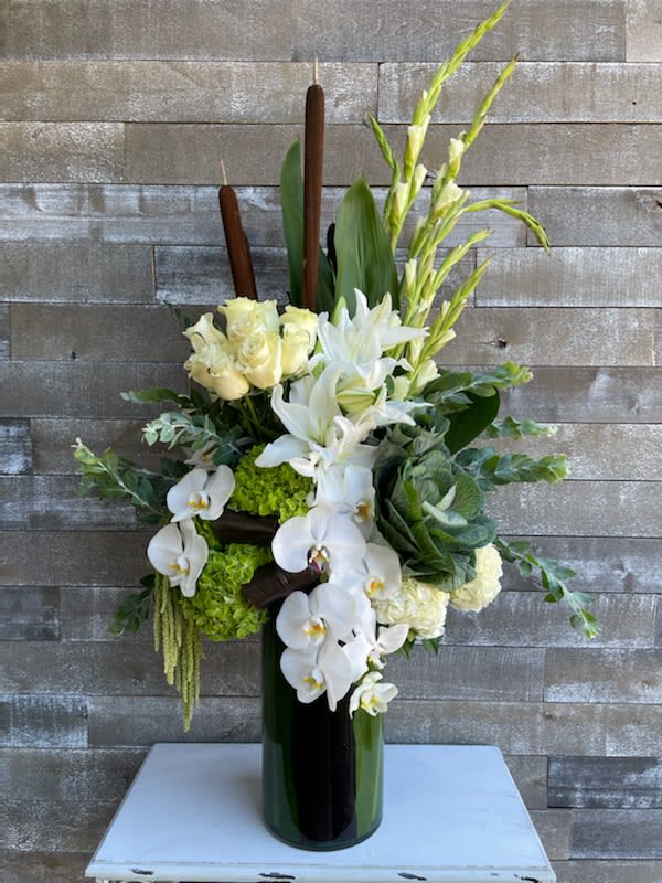 White orchids, lilies, and roses arranged in a tall vase