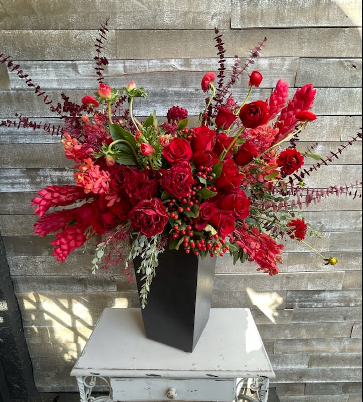 Large red floral arrangement in a tall black vase