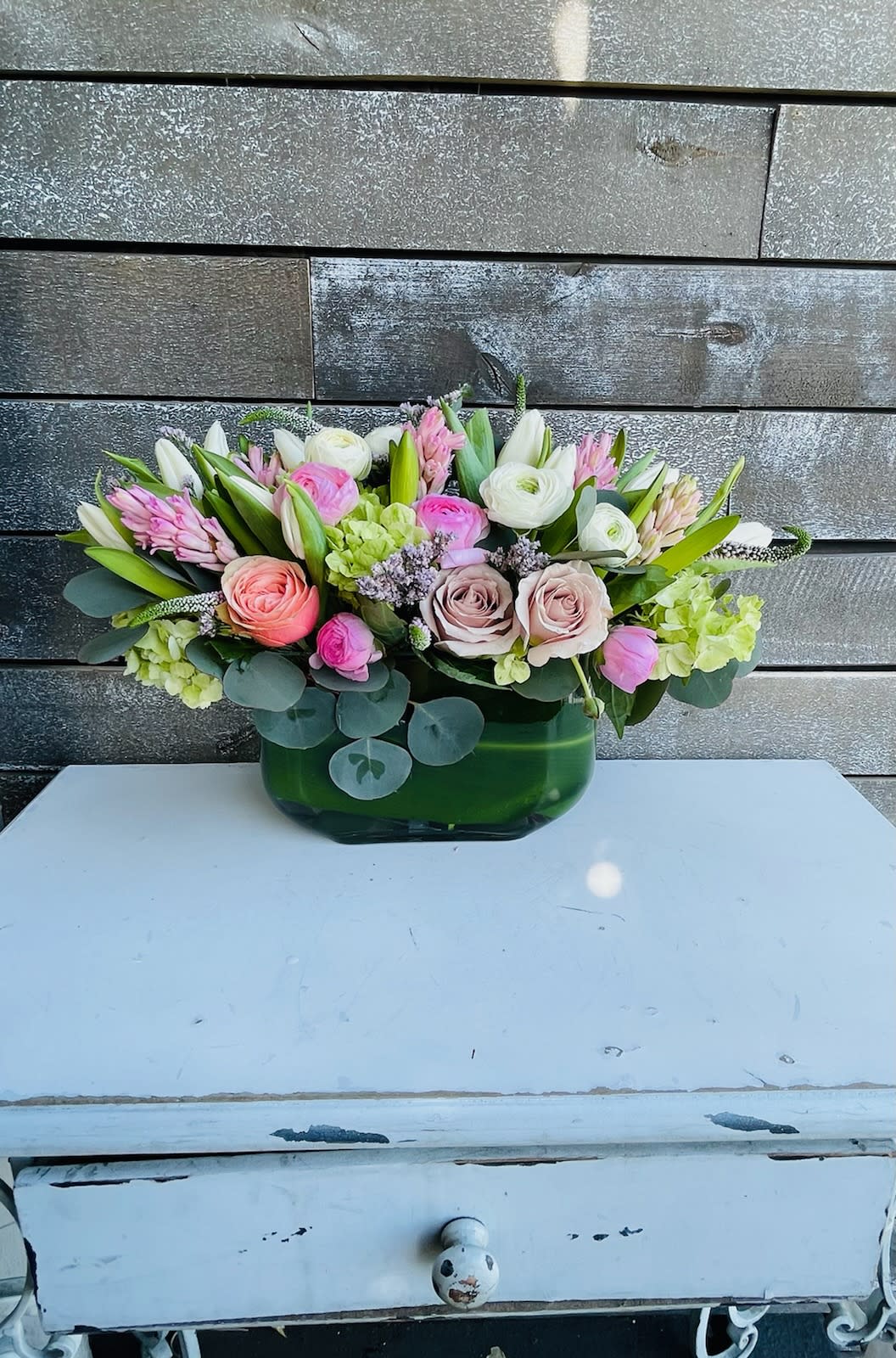 Mixed pink and white flower arrangement in a green glass vase