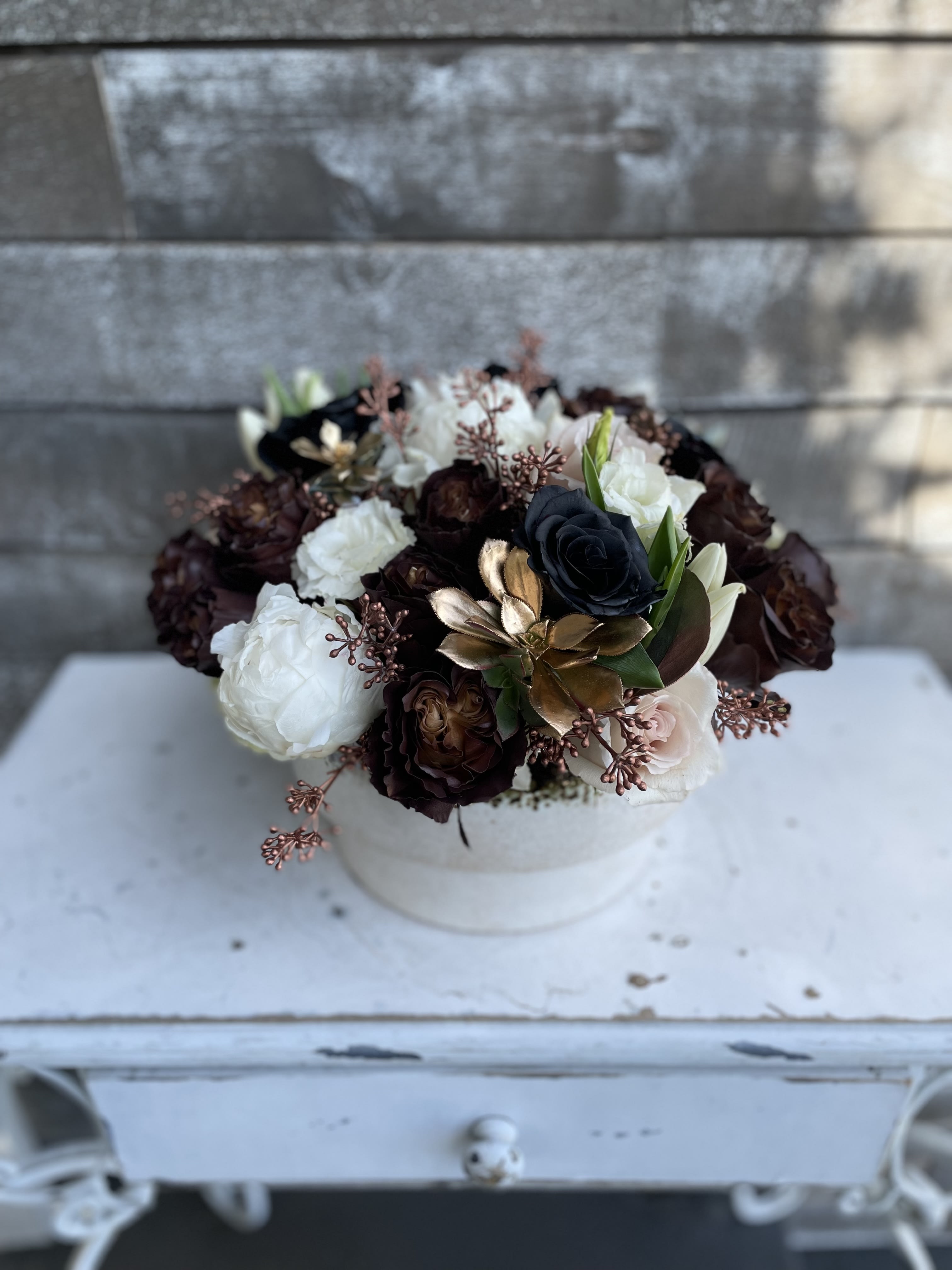 Round bouquet of white, blush, and dark roses in a white box