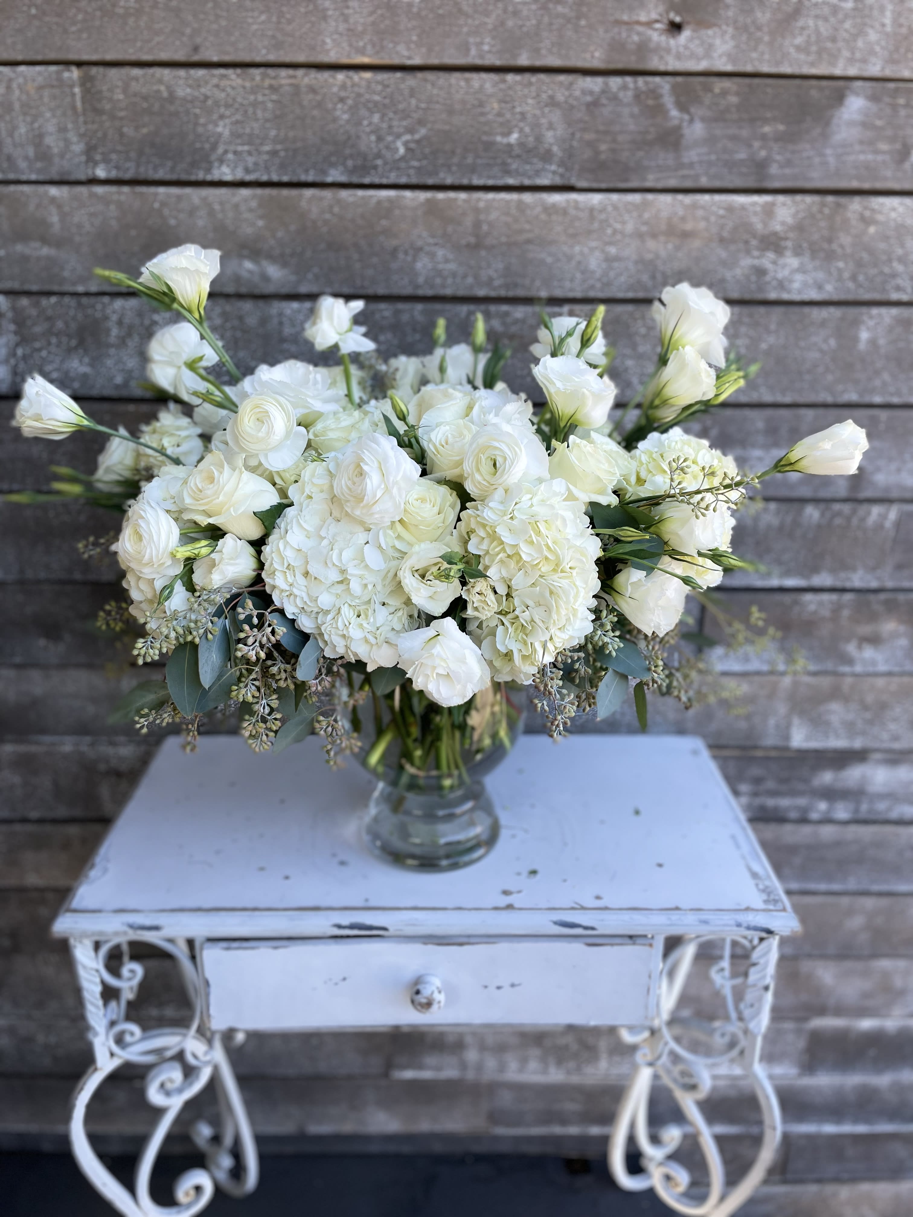 White floral arrangement in a clear glass vase on a small table