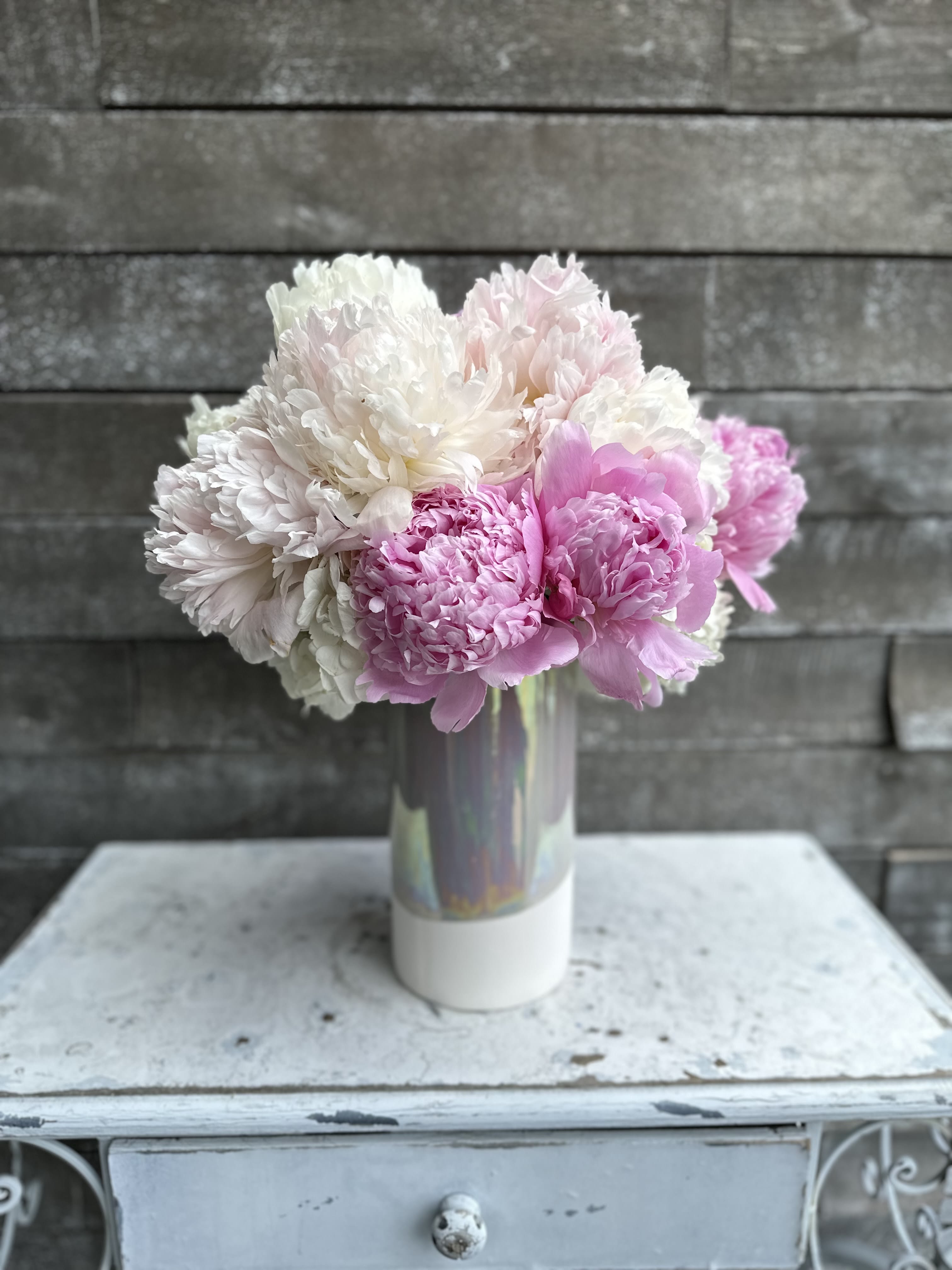 Pink and white peonies in a tall vase
