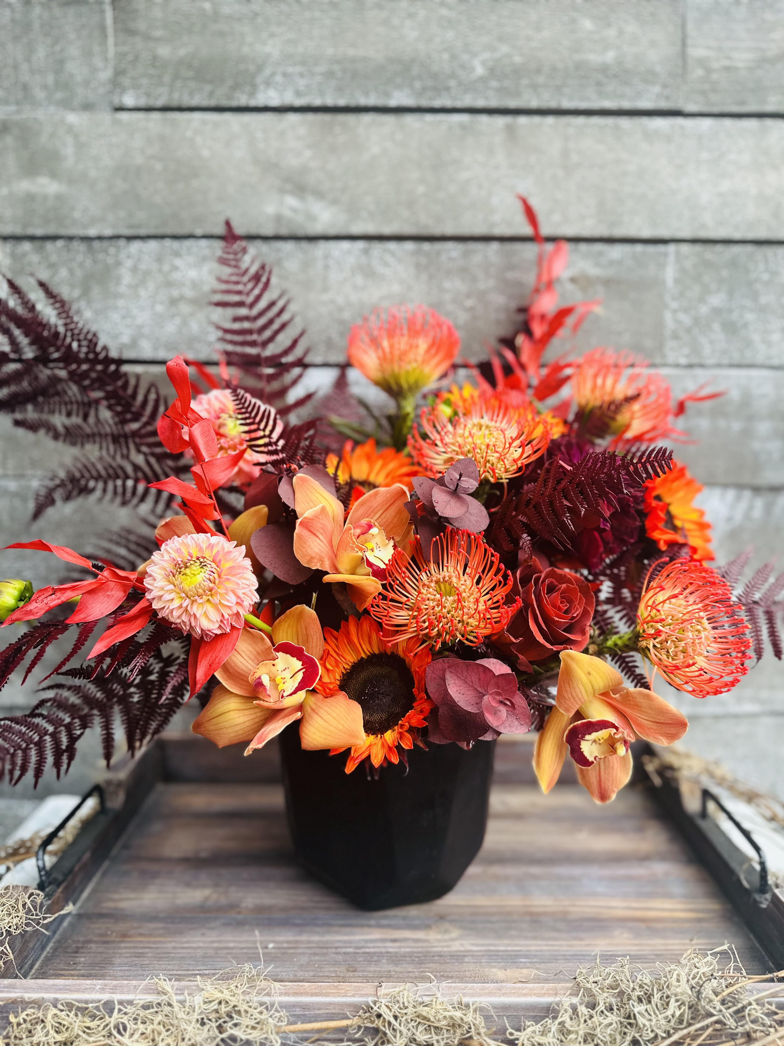 Orange and red floral arrangement in a black vase