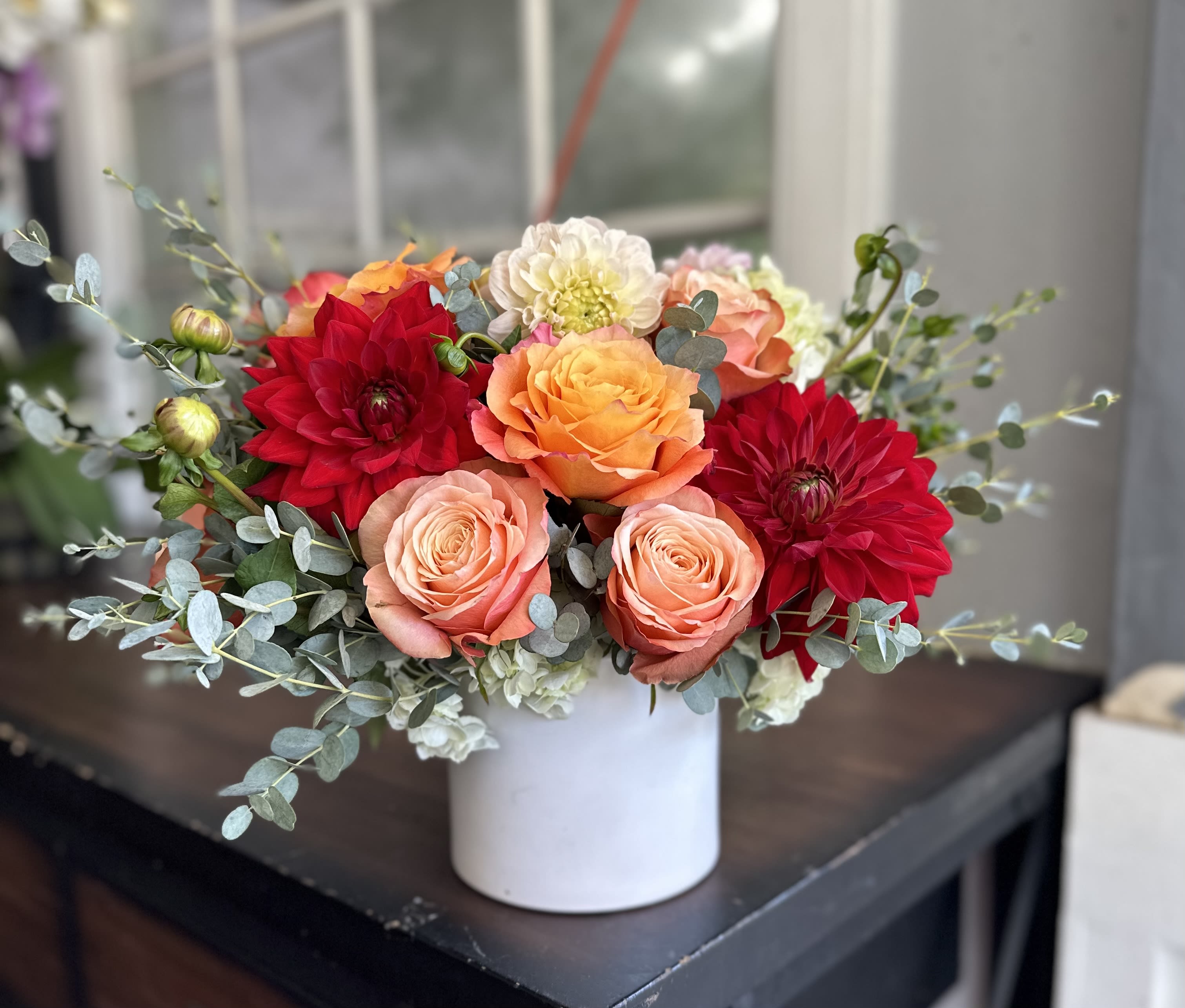 Bouquet of red, peach, and orange flowers in a white vase