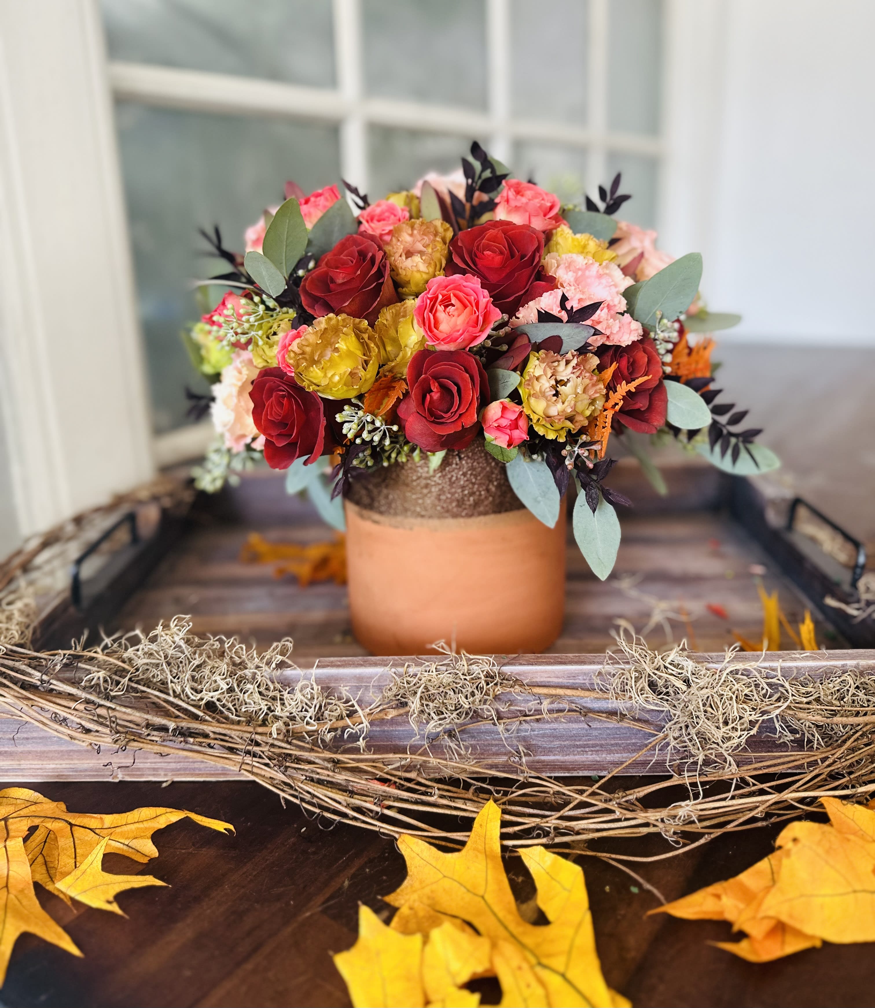 Bouquet of red, pink, and yellow roses in a copper-toned vase