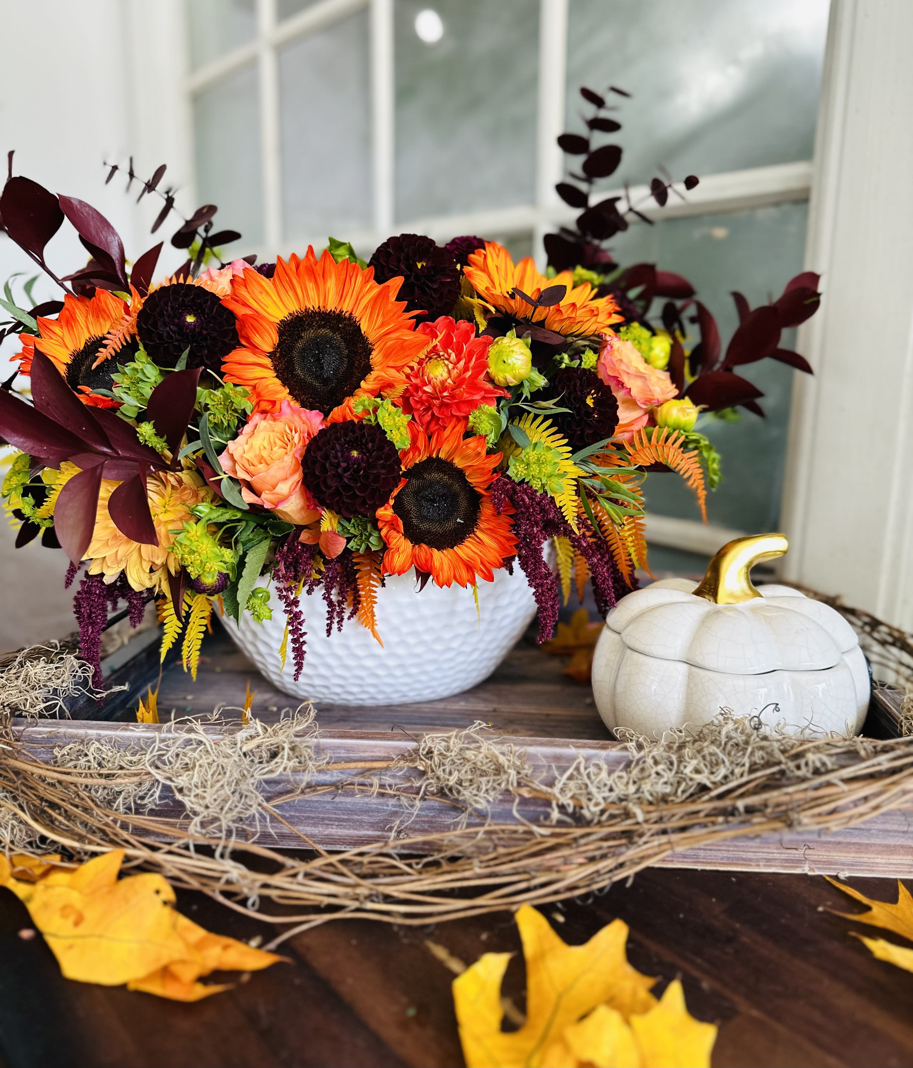 Bright autumn floral arrangement in a white bowl beside a white pumpkin decor piece