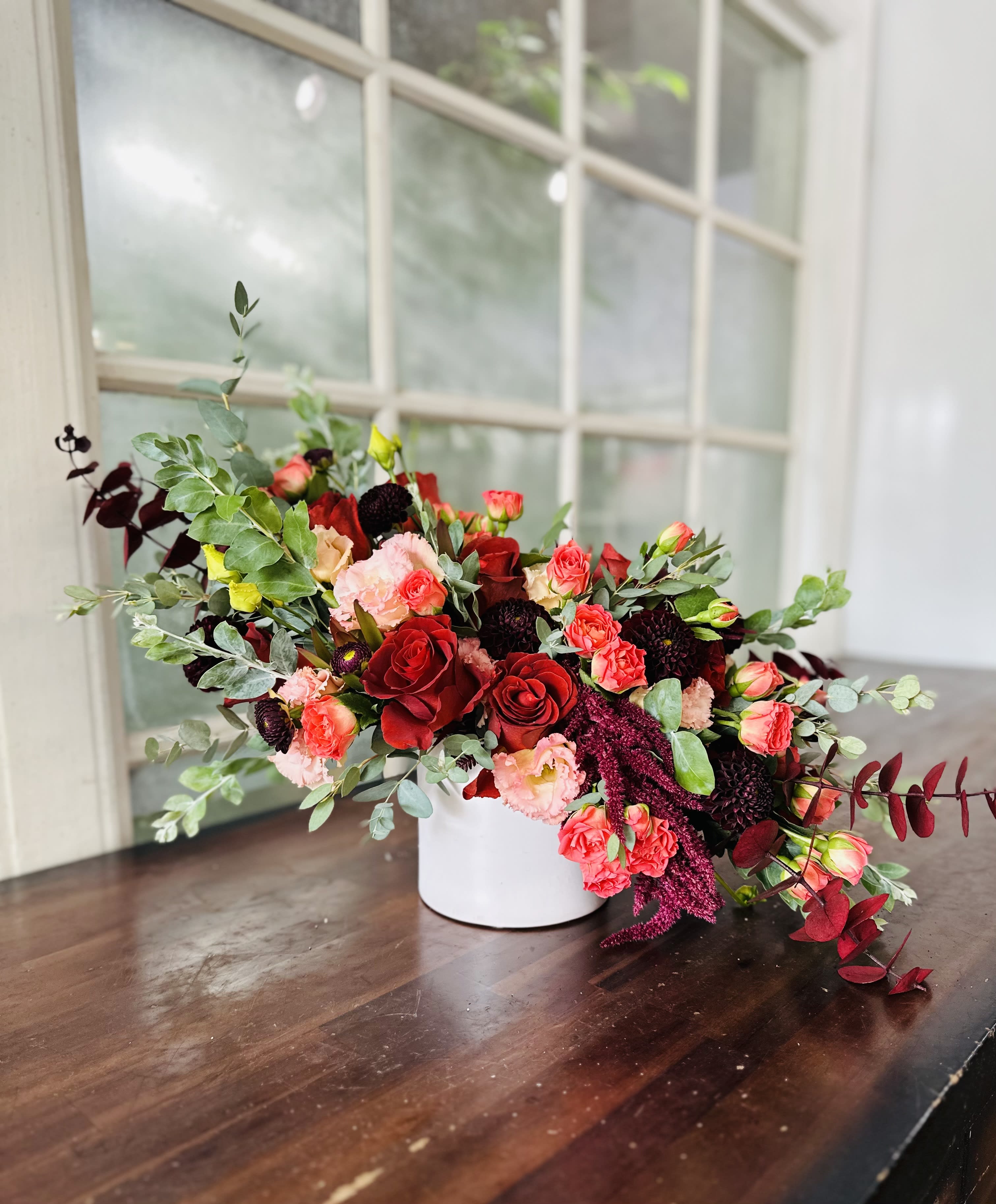 Mixed red and pink floral arrangement in a white vase