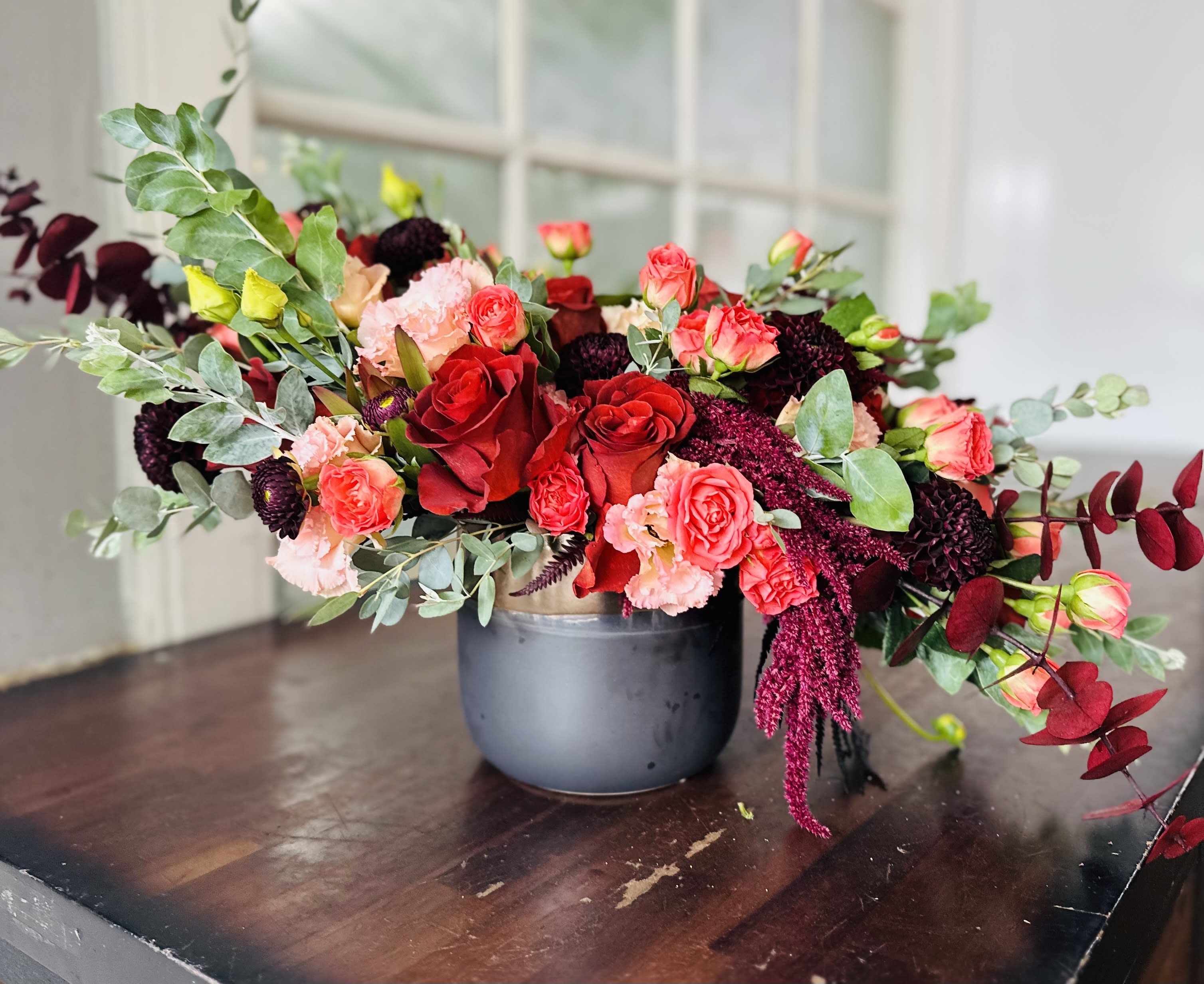 Mixed bouquet of red and pink roses in a gray vase