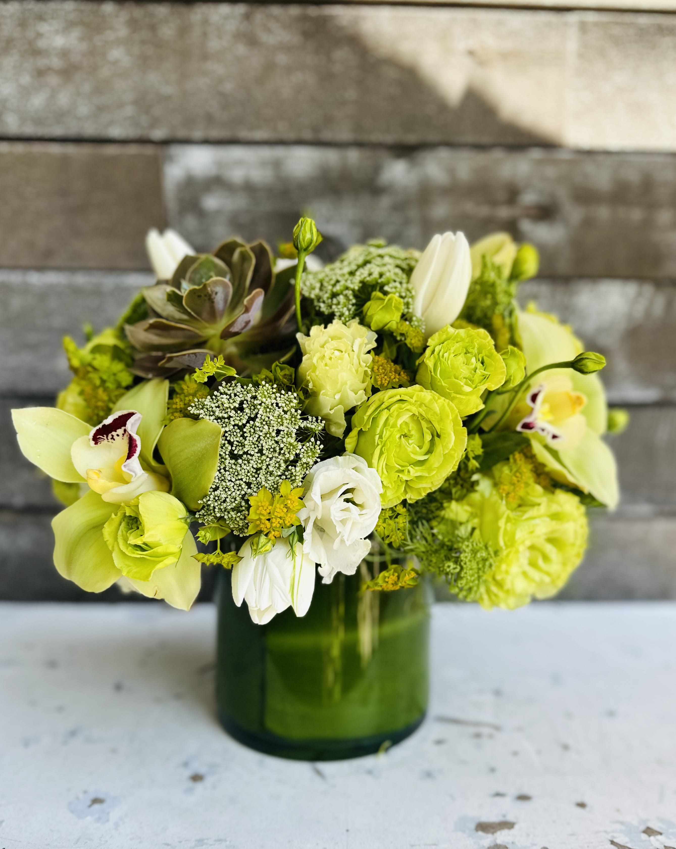 Green and white floral arrangement in a glass vase