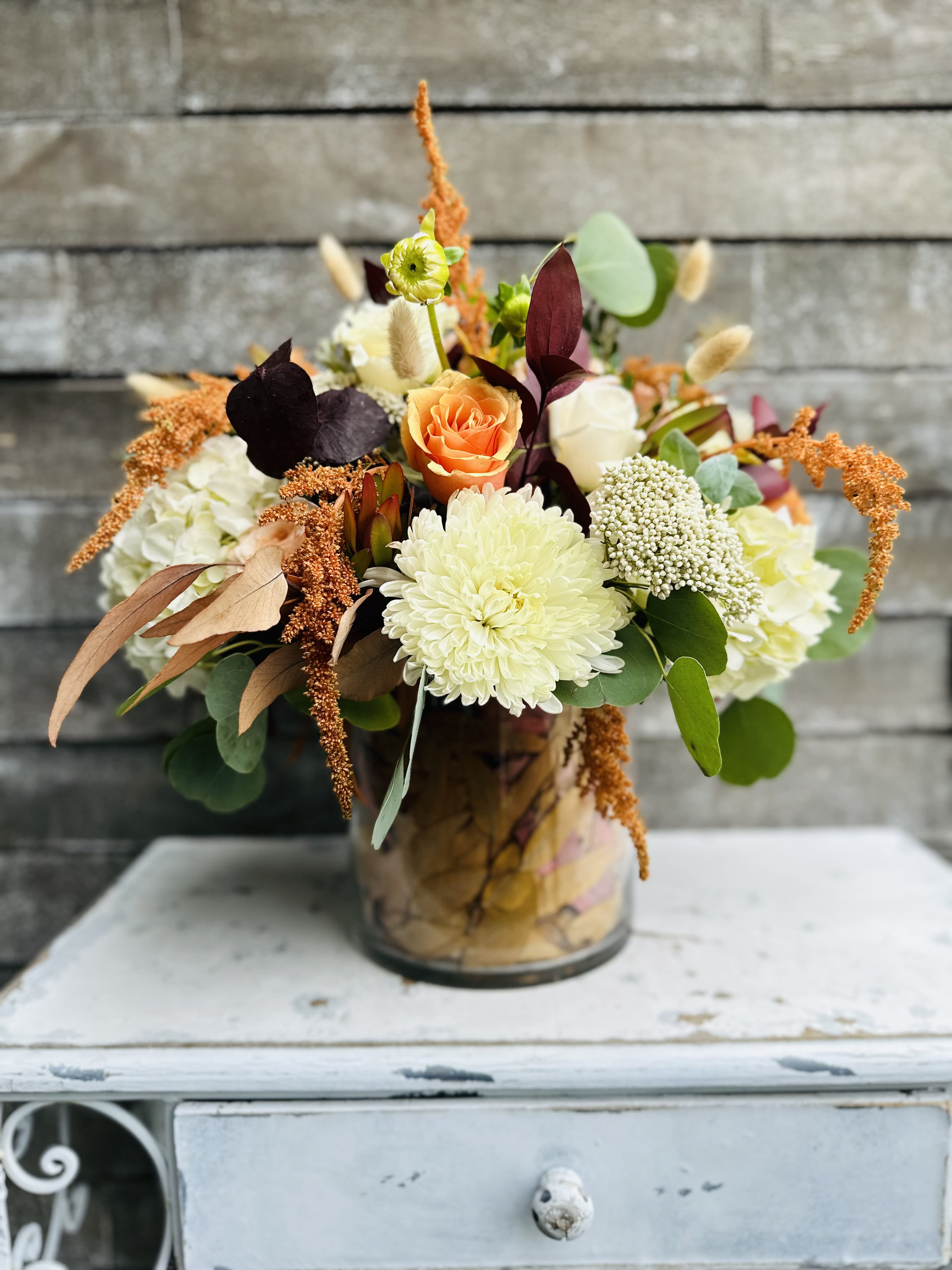 Mixed floral arrangement in a glass vase with orange and white blooms
