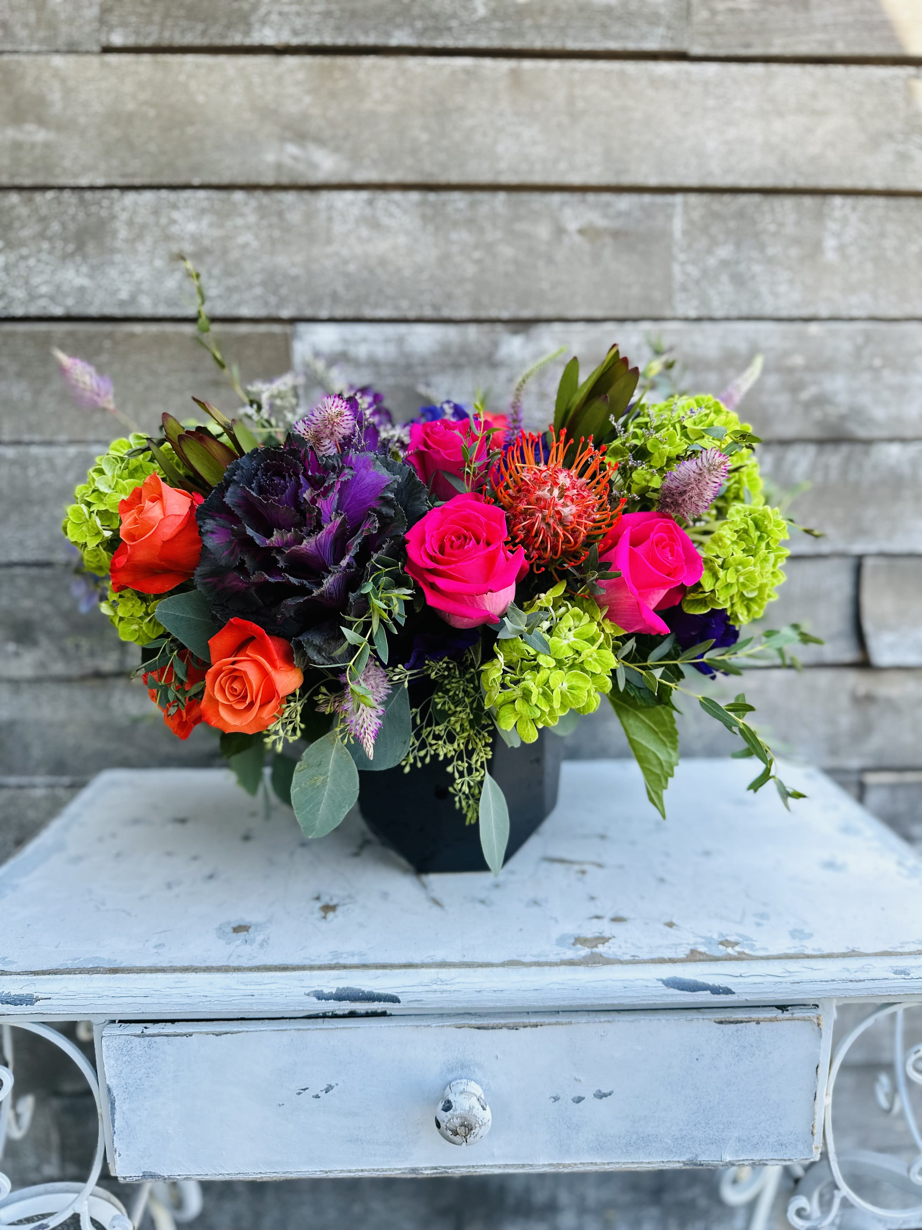 Colorful mixed bouquet in a black container with roses and bright green blooms