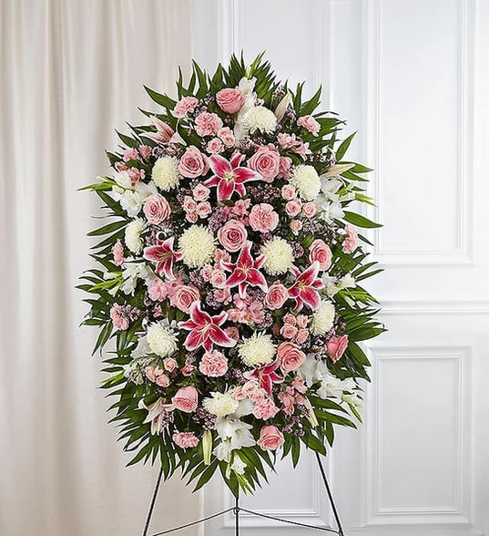 Standing floral spray with pink roses, white lilies, and red lilies