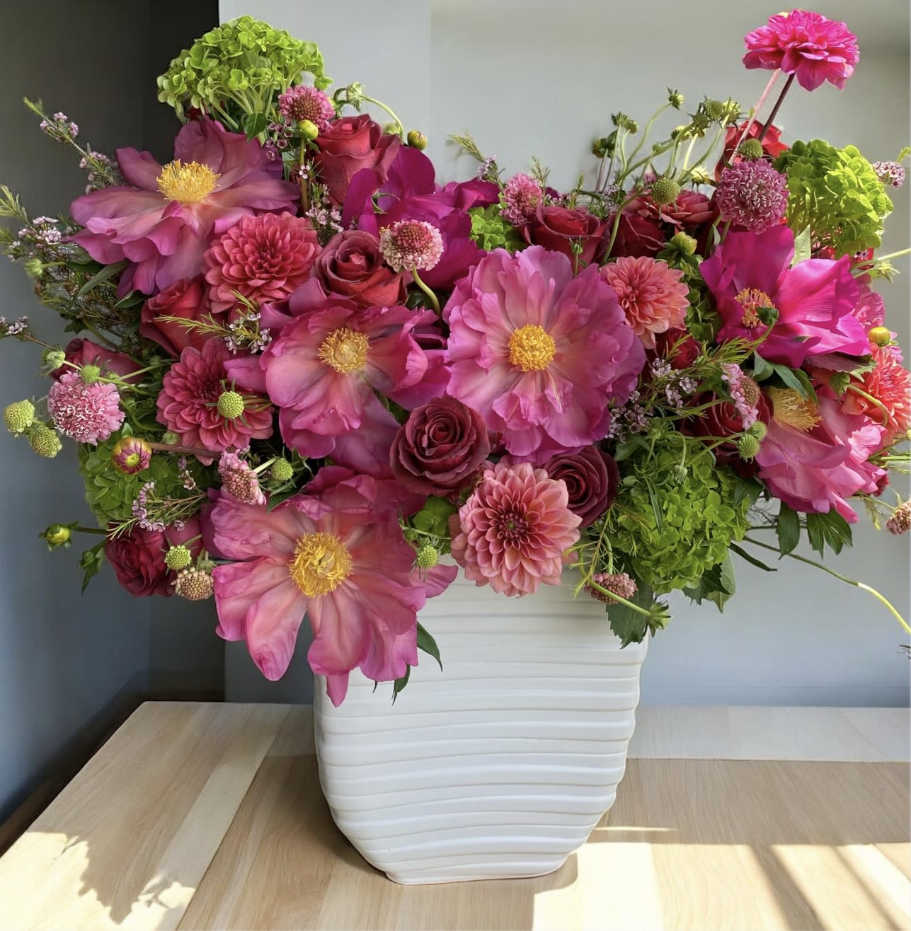 Pink and magenta flowers arranged in a white vase