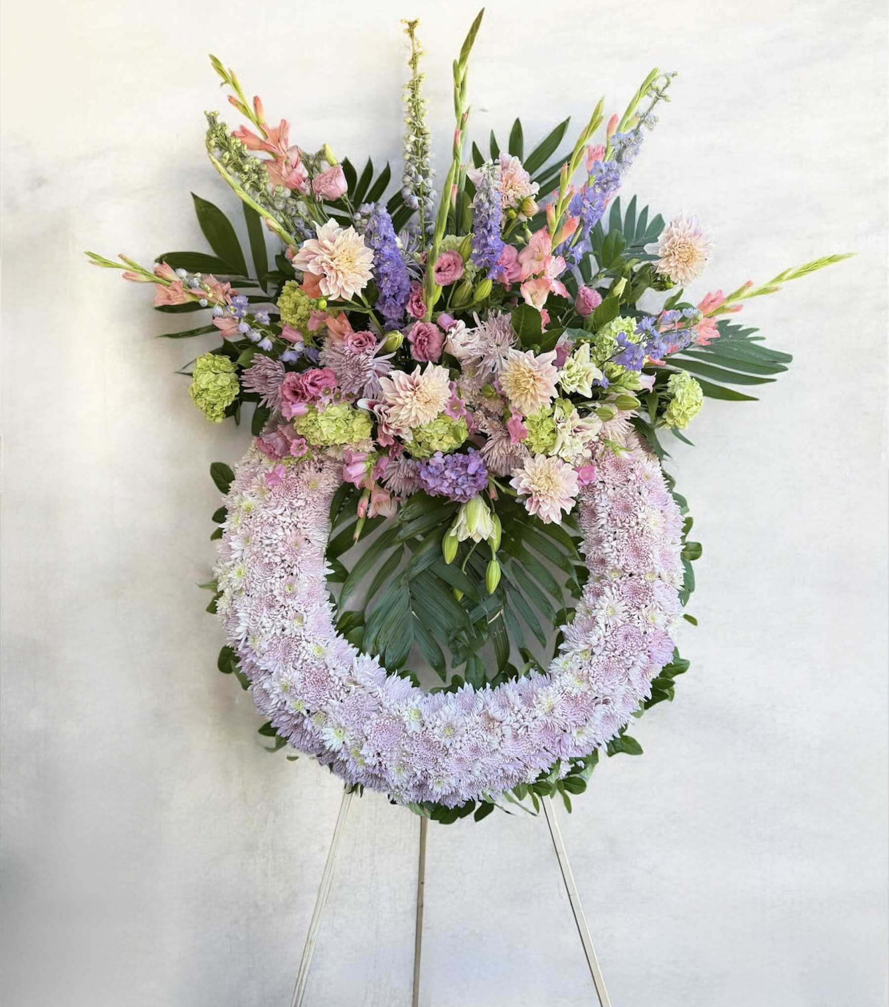 Large pastel floral wreath on an easel with pink, lavender, and green blooms