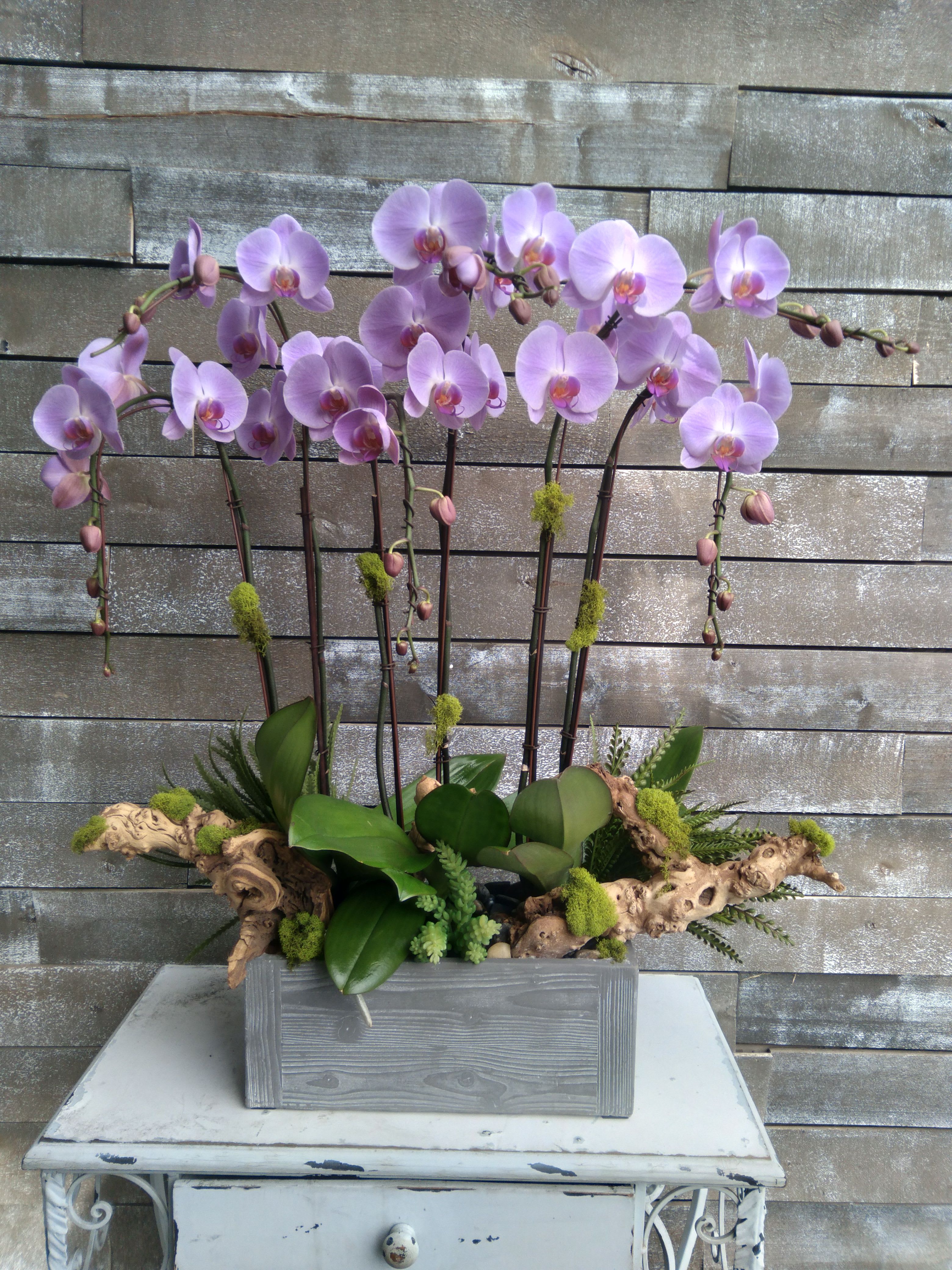 Lavender orchid arrangement in a gray wooden planter