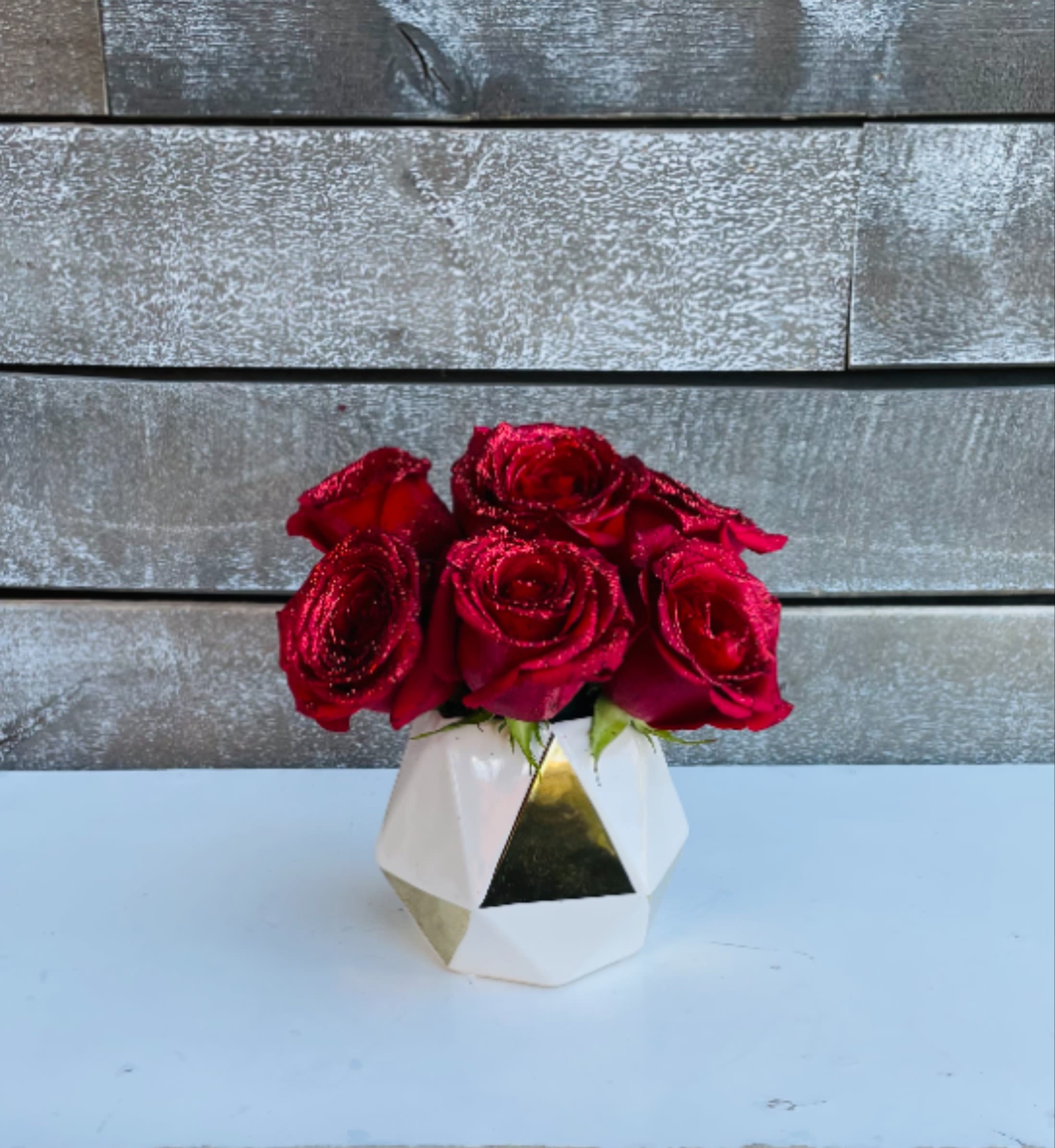 Red roses in a geometric white vase with gold accents
