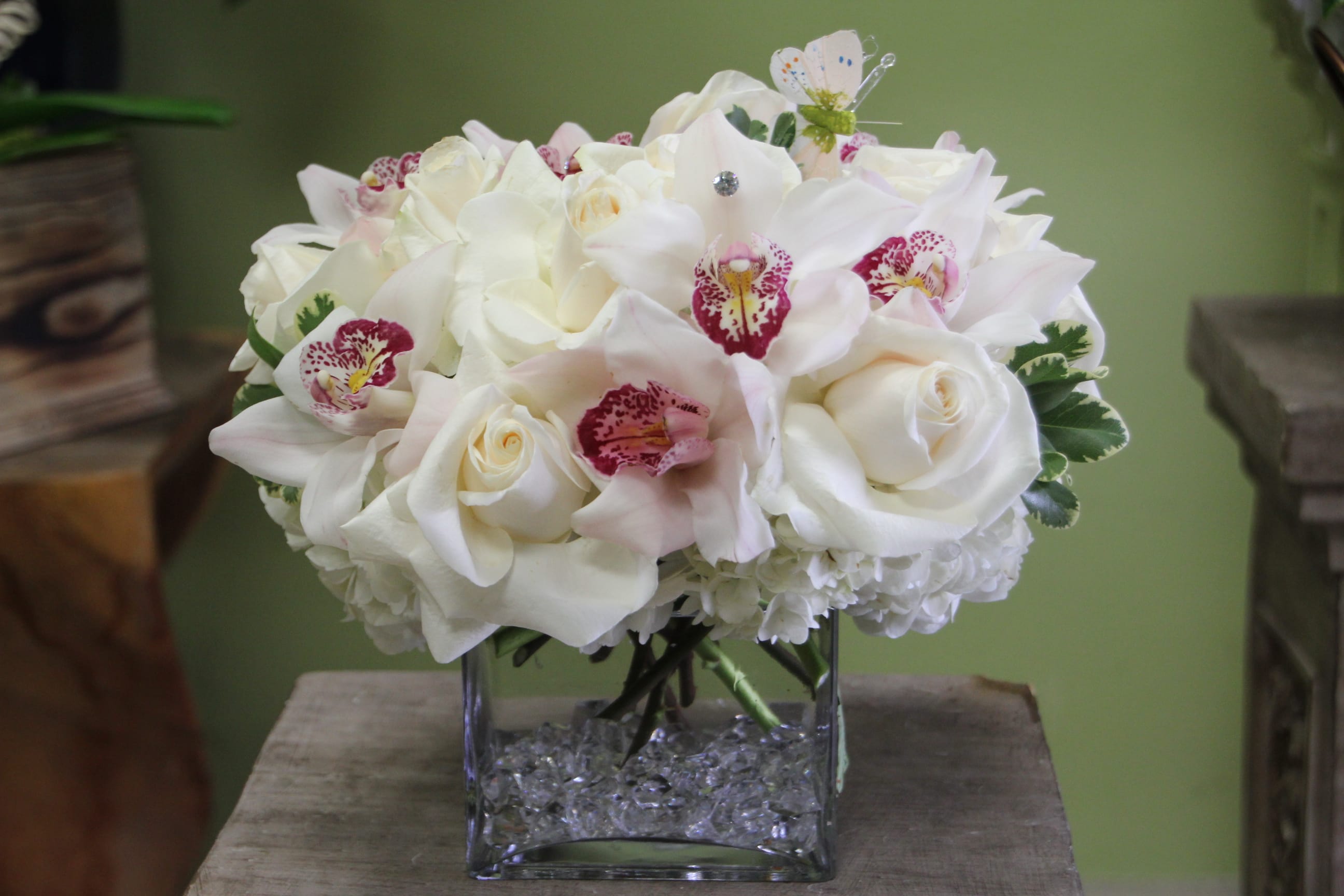 White floral bouquet in a square glass vase with crystal filler