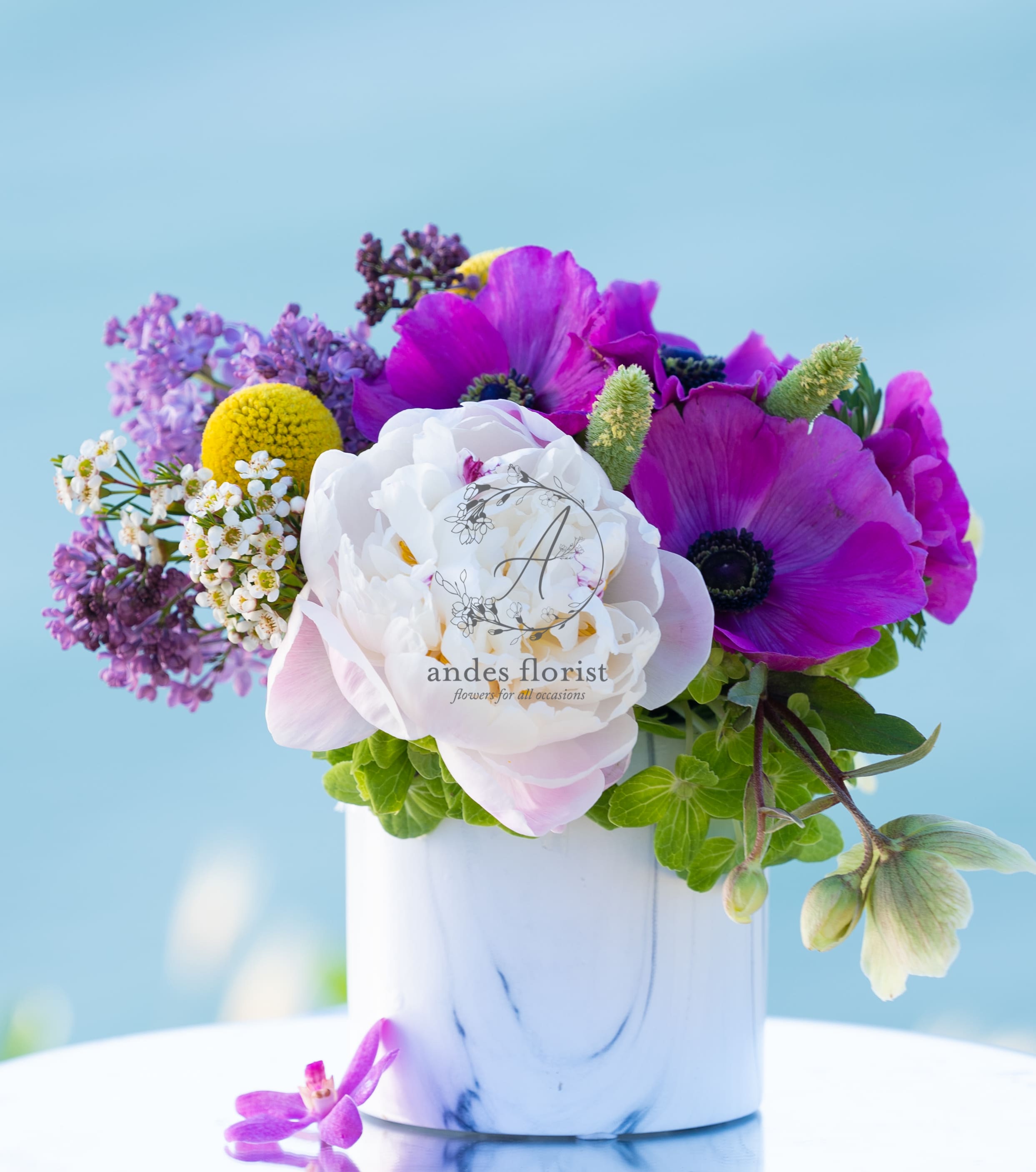 Purple and white flowers arranged in a white vase