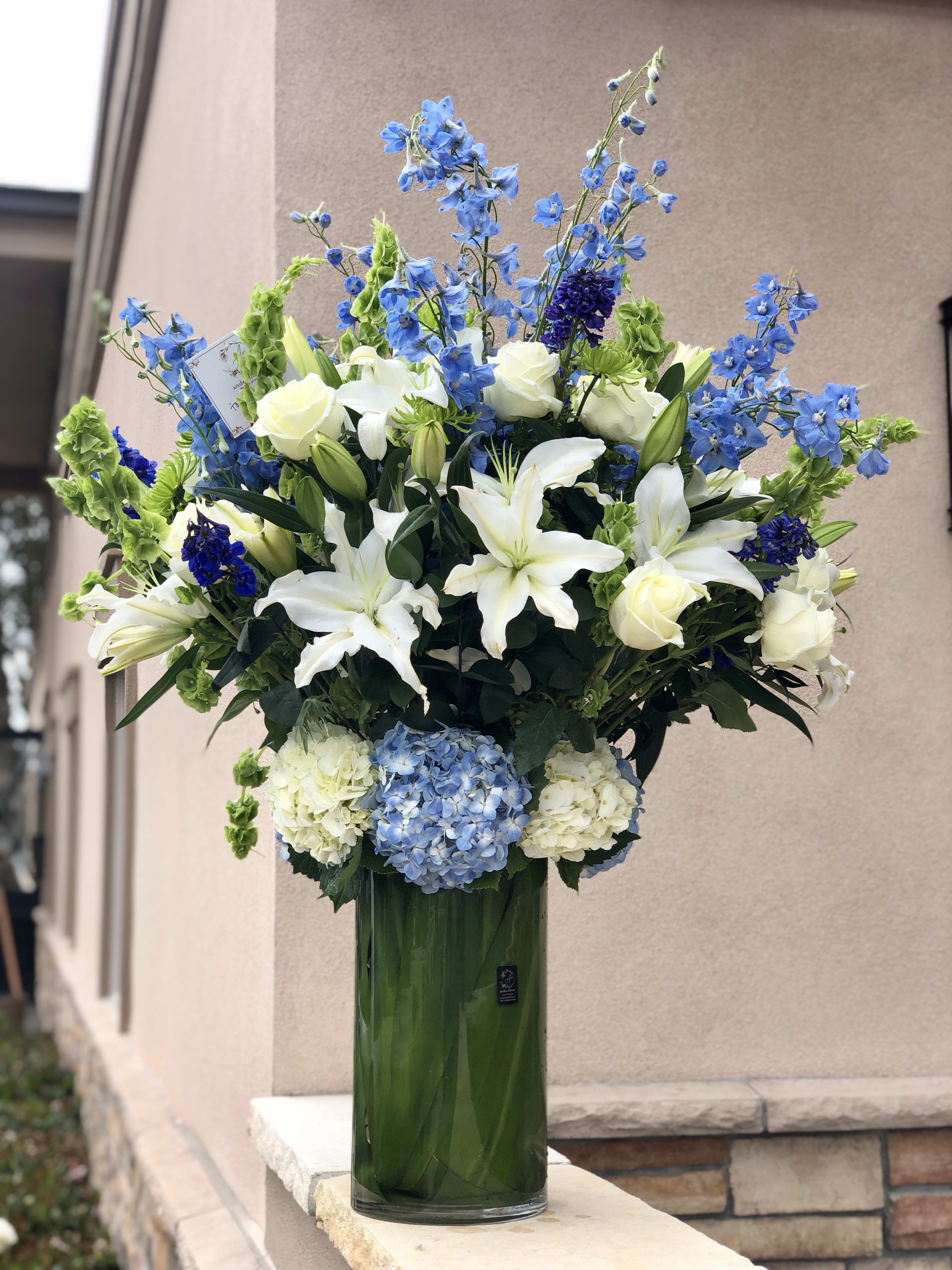Tall blue and white floral arrangement in a glass vase