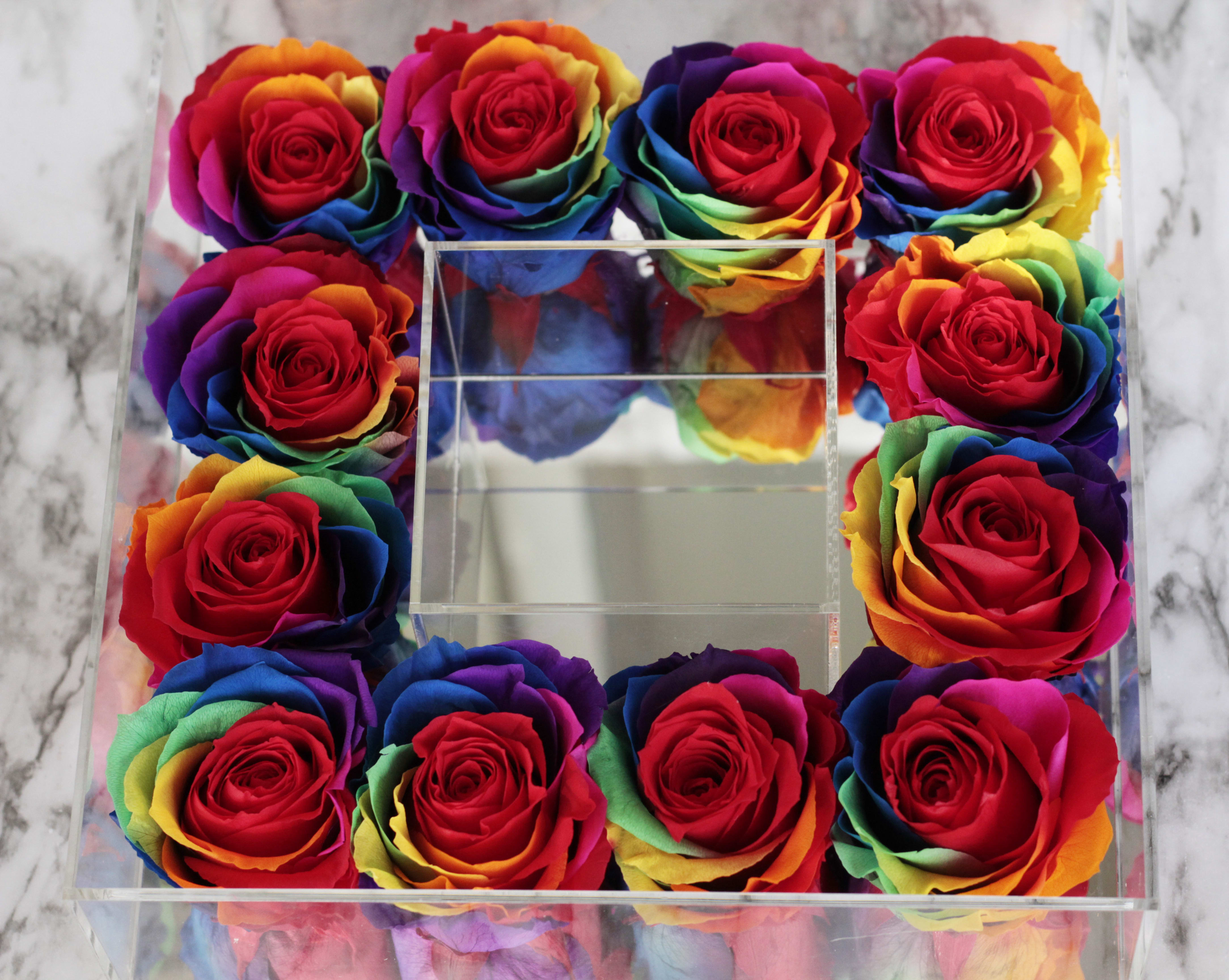 Rainbow-colored roses arranged in a clear square box