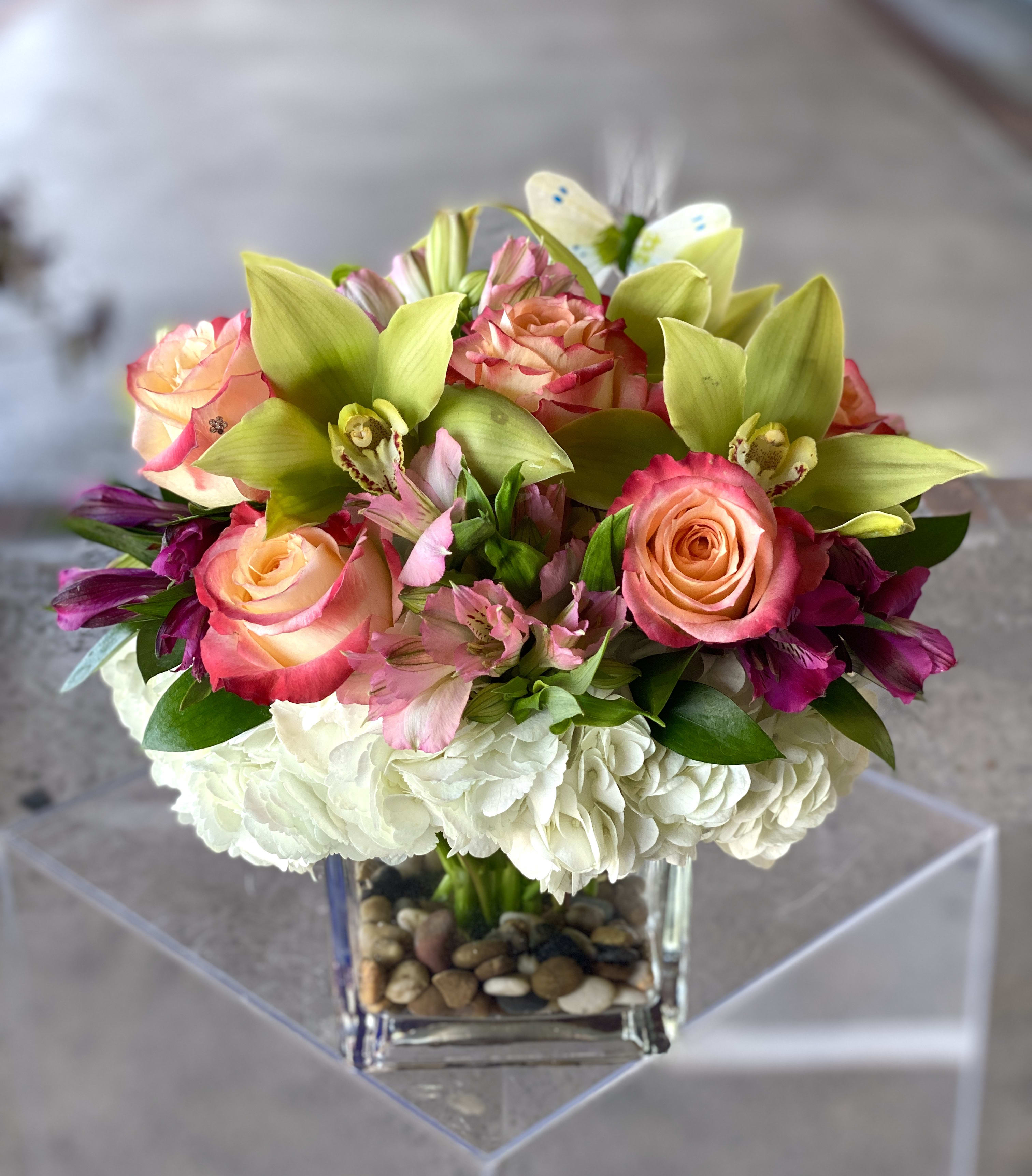 Bouquet of pink roses, orchids, and white hydrangeas in a glass vase