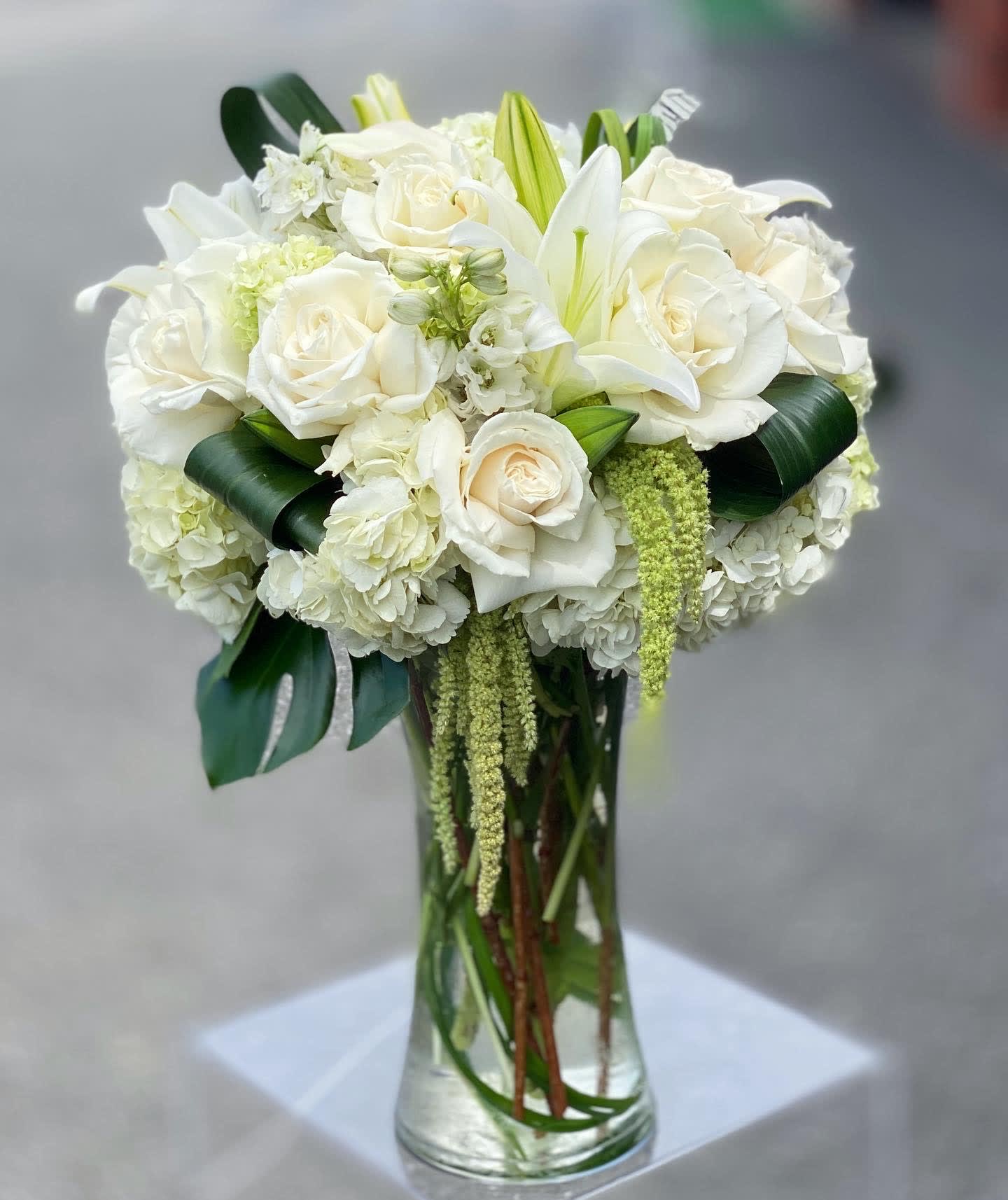 White roses and lilies arranged in a clear glass vase