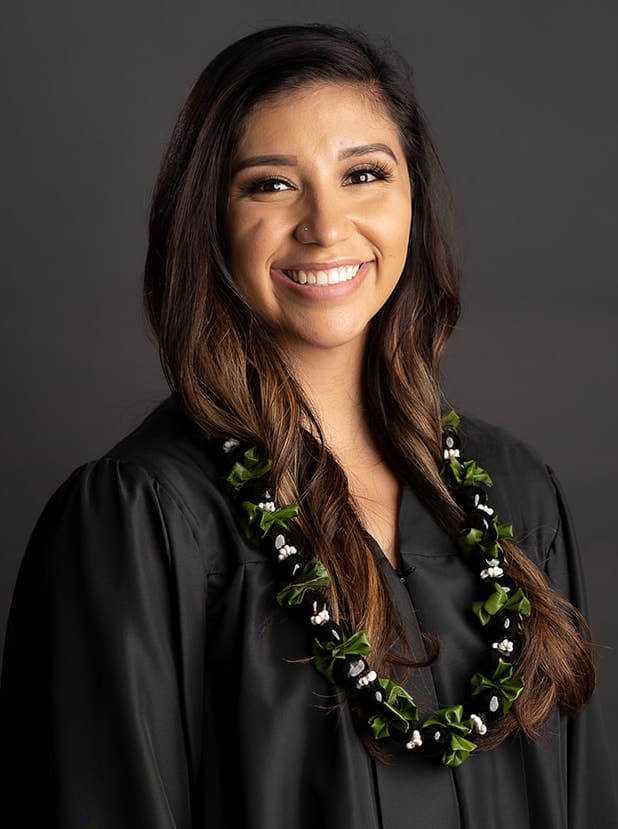 Woman in a black graduation gown wearing a floral lei